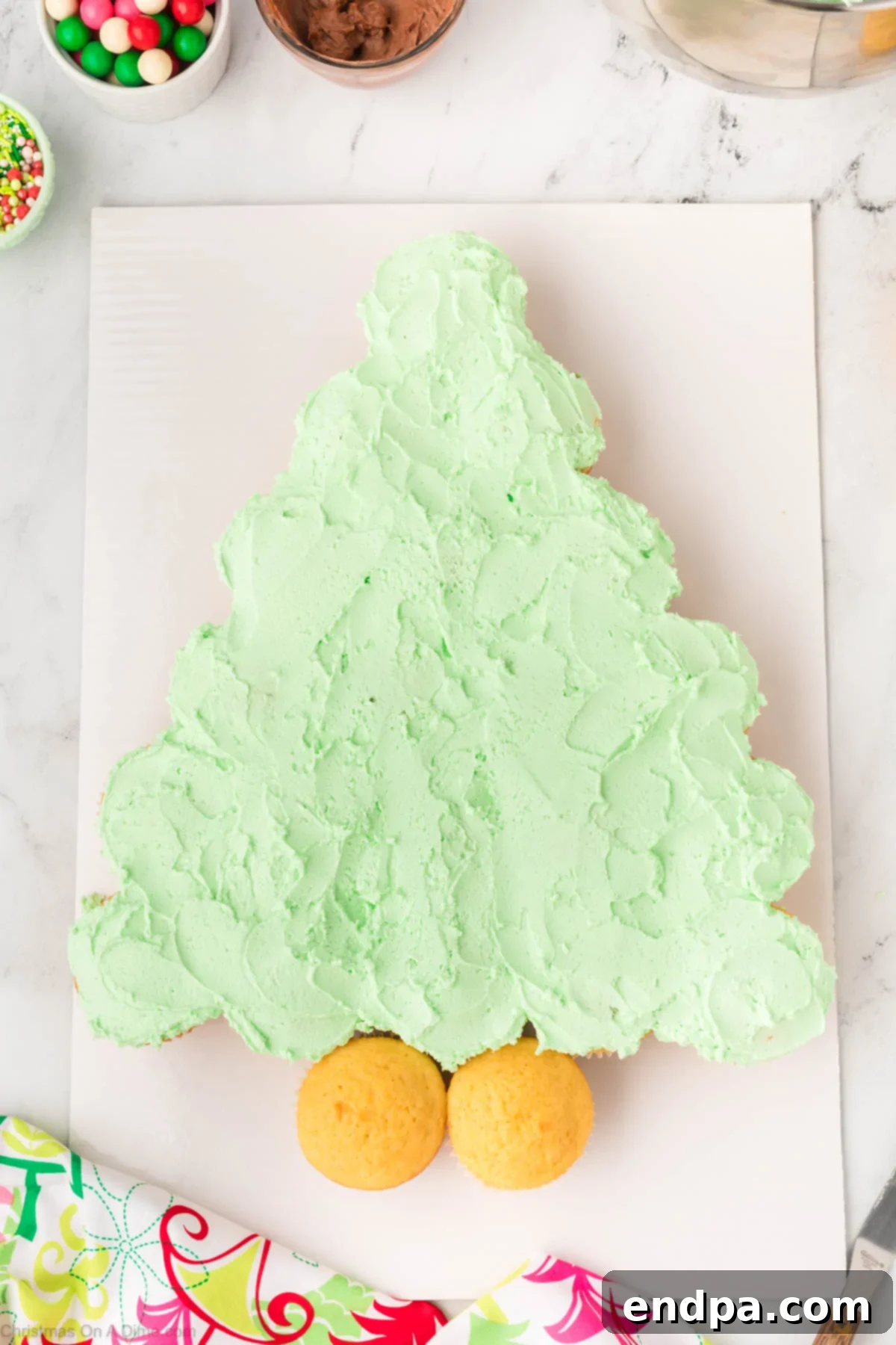 Green frosting being smoothly spread across the arranged cupcakes to create a unified tree shape.