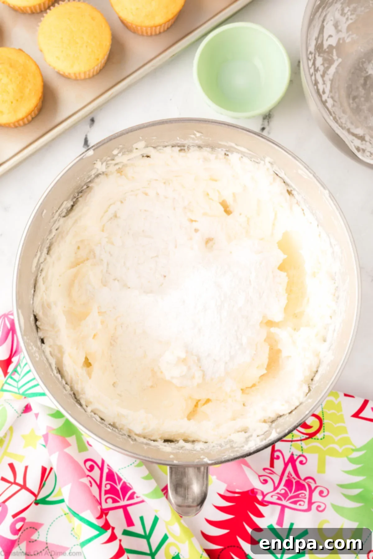 Powdered sugar being added to the whipped butter and shortening mixture.