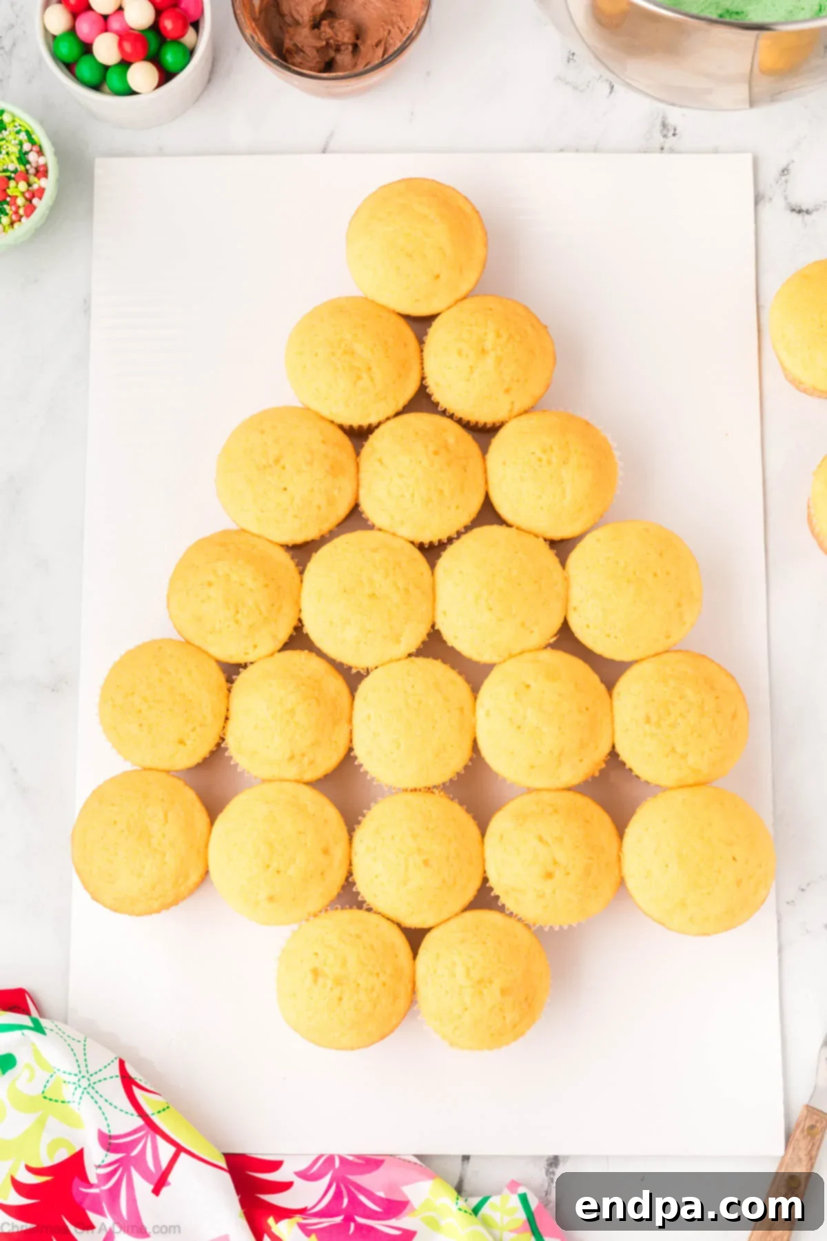 Cooled cupcakes arranged in the shape of a Christmas tree on a platter.