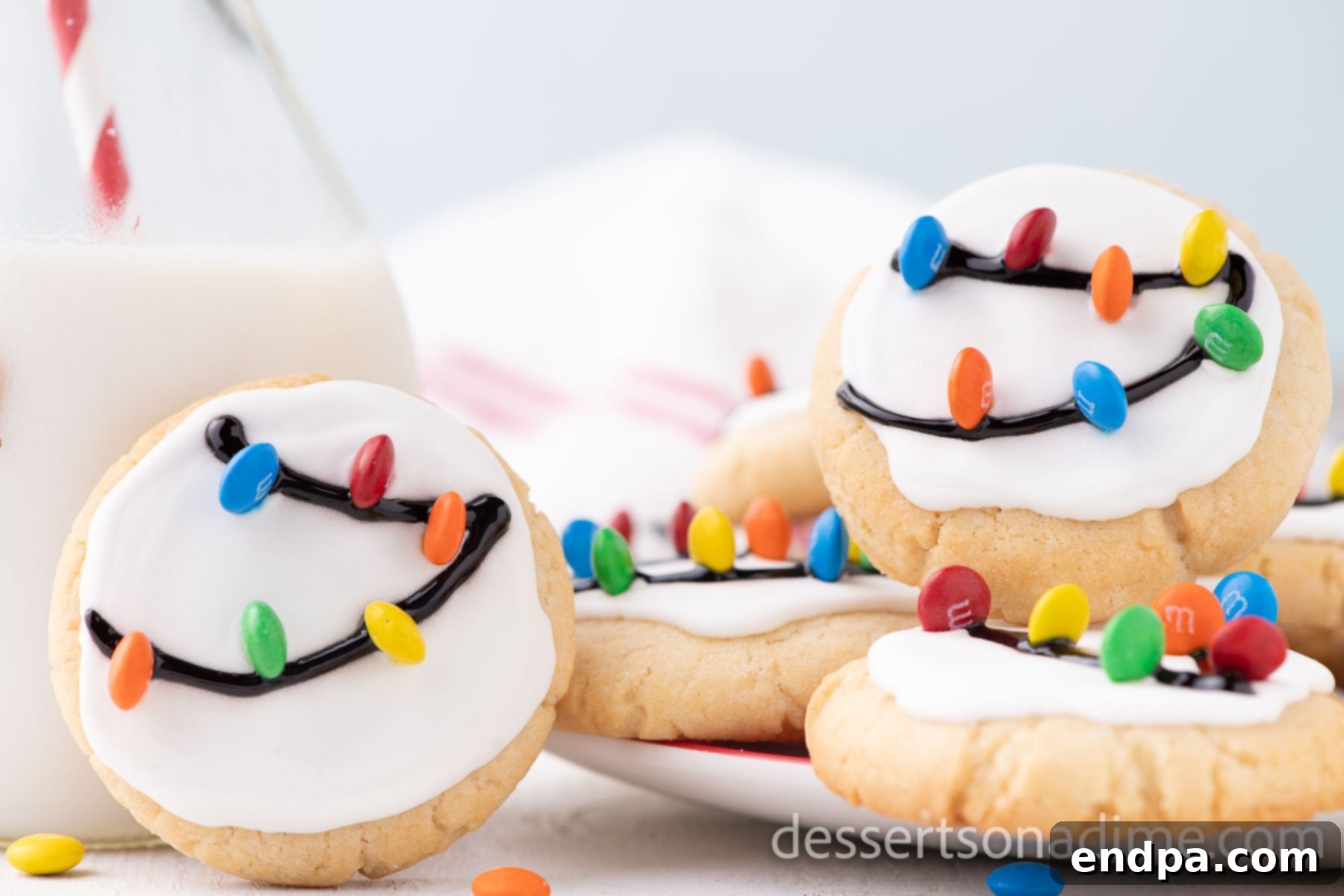 A festive platter adorned with beautifully decorated Christmas light cookies, featuring colorful candy lights on white icing.