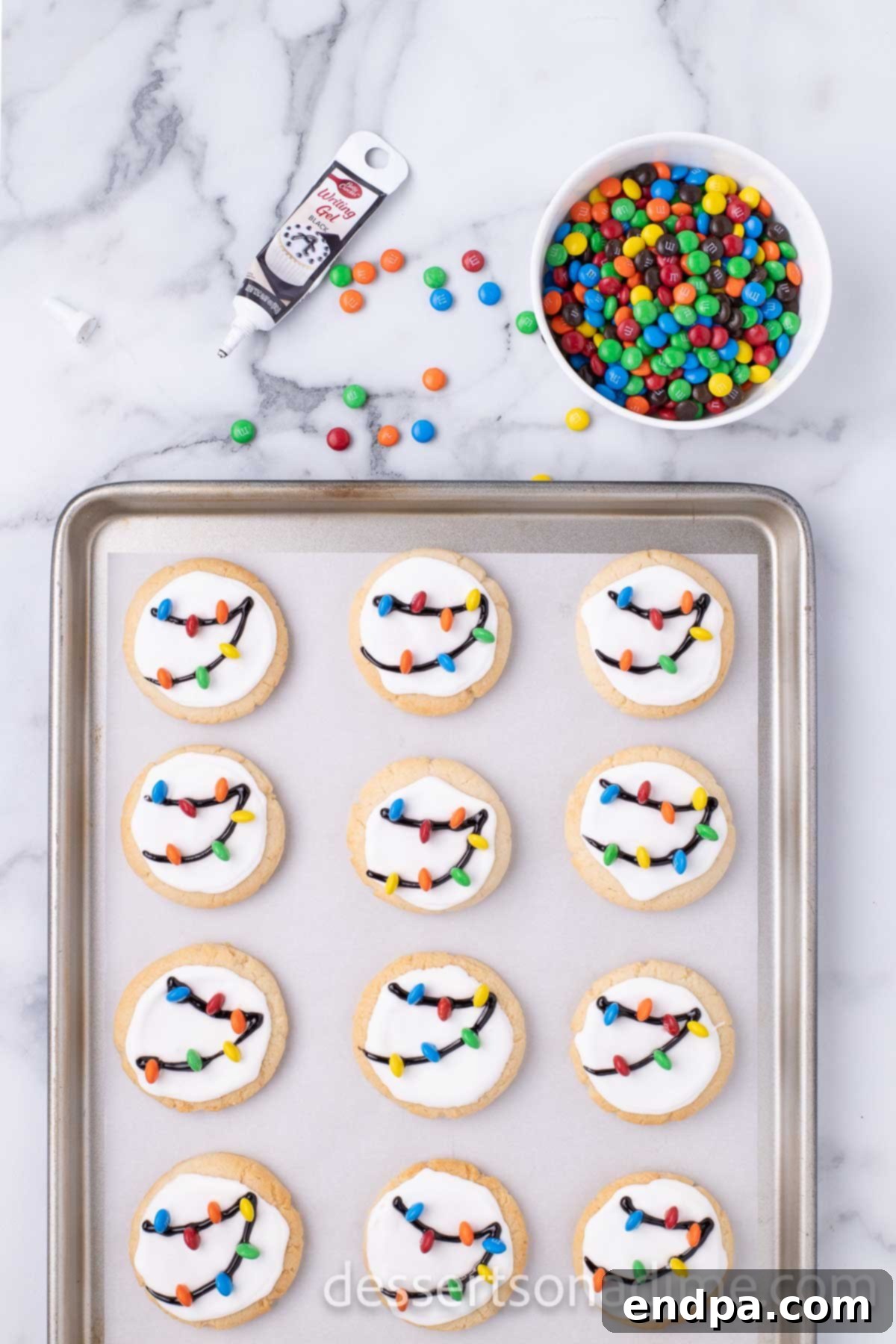 Decorated Christmas light cookies with black gel lines forming the 'strings' and colorful mini M&M's representing the 'lights'.