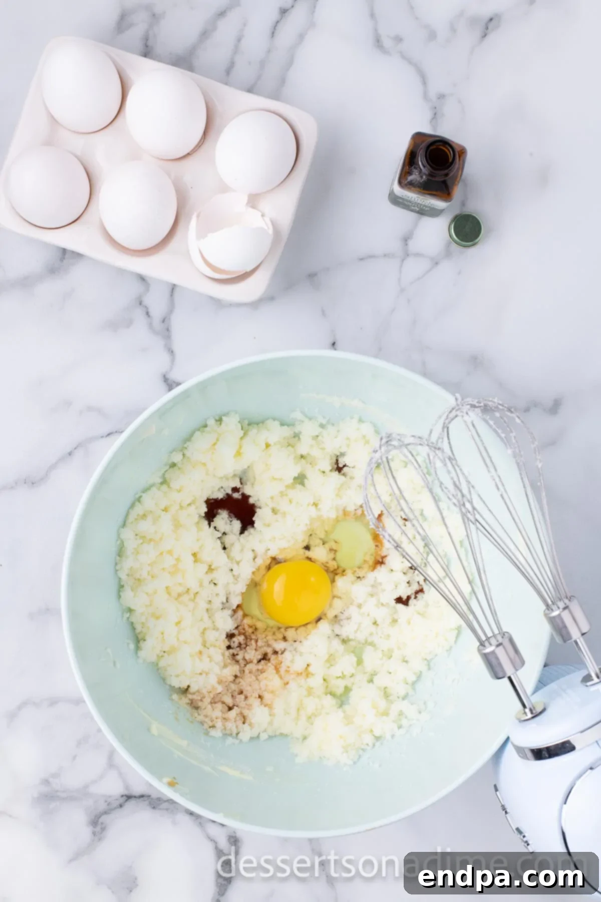 A mixing bowl where softened butter and sugar are being creamed together, with an egg about to be added to the mixture.