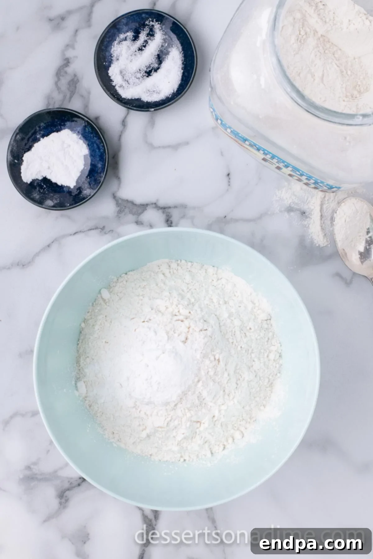 A separate mixing bowl contains the dry ingredients, including flour, baking powder, and salt, whisked together.