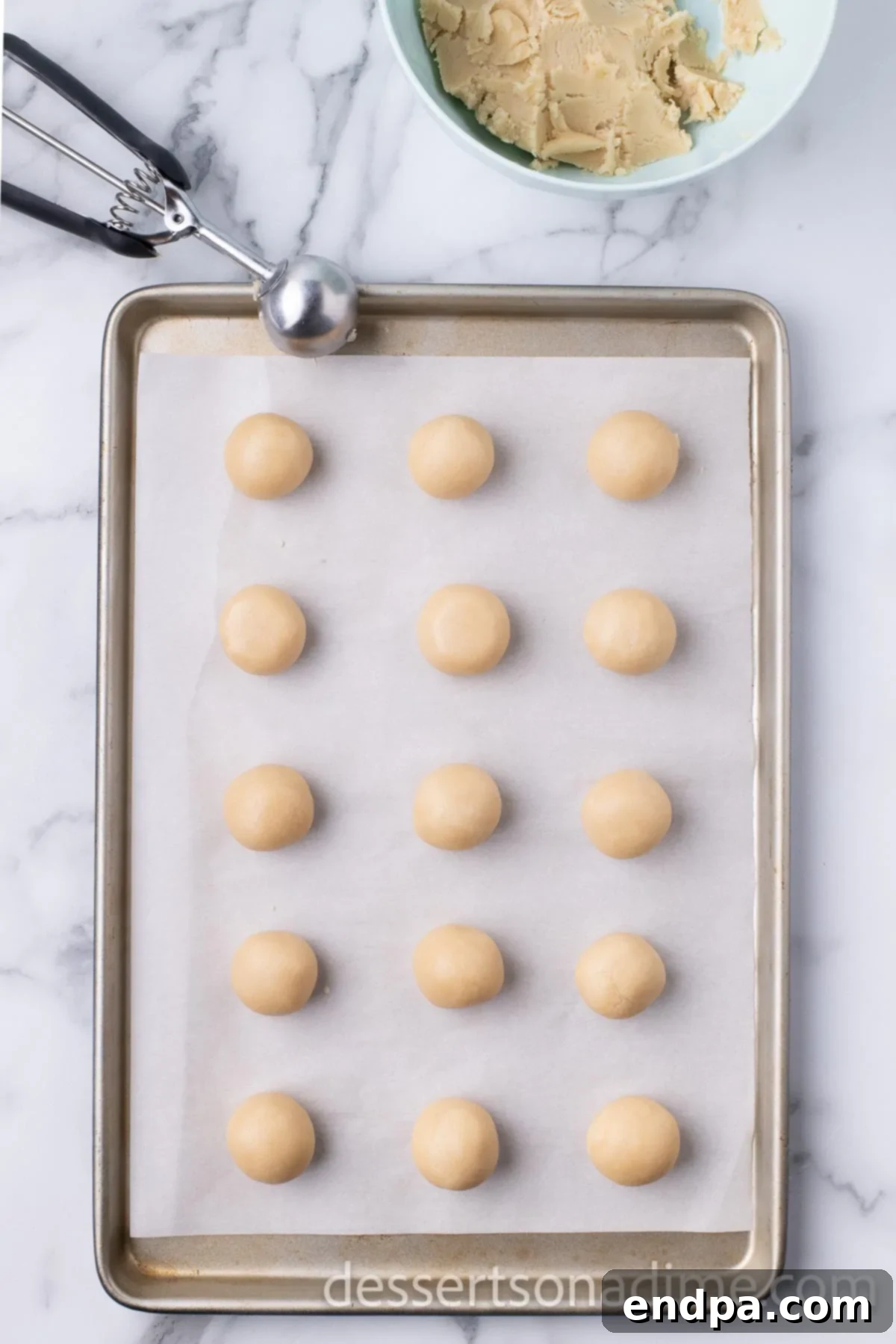 A baking sheet is prepared with uniform balls of cookie dough, ready for chilling and baking.