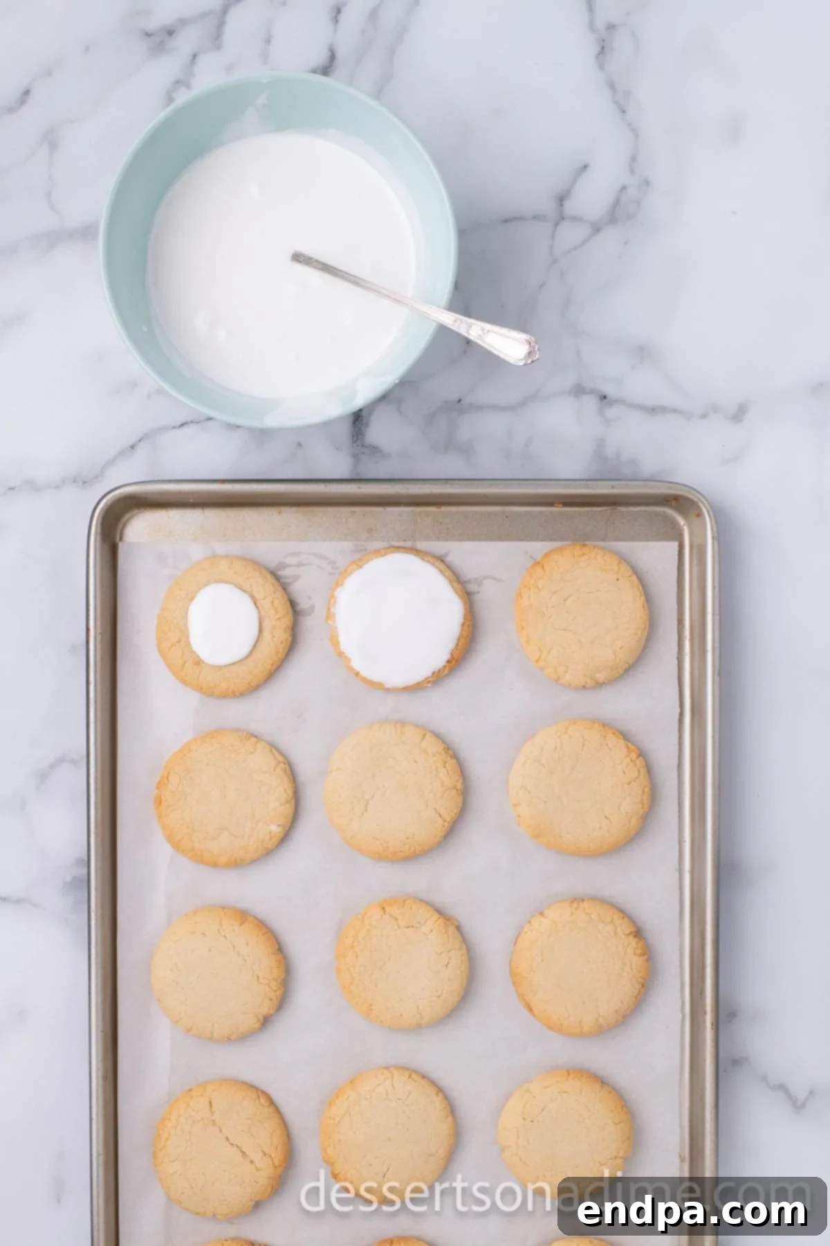 Cooling cookies are covered with a smooth layer of white royal icing, drying on a wire rack.