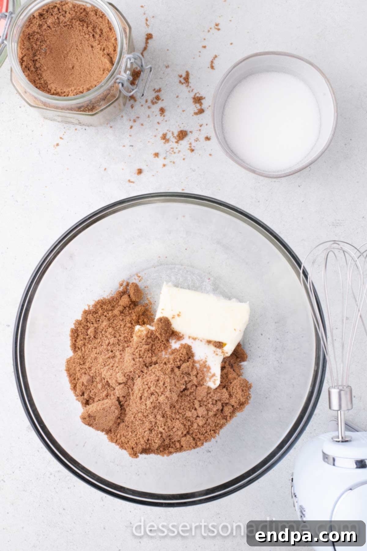 Mixing bowl with softened butter, granulated sugar, and brown sugar being creamed together.