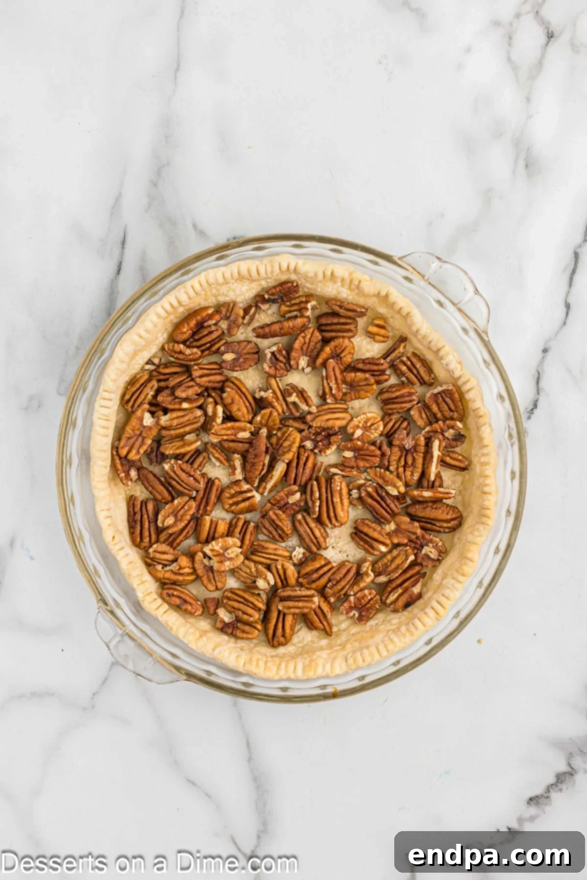 Paula Deen's Southern Comfort Pecan Pie 4 Pecans layered on the bottom of a pie crust.