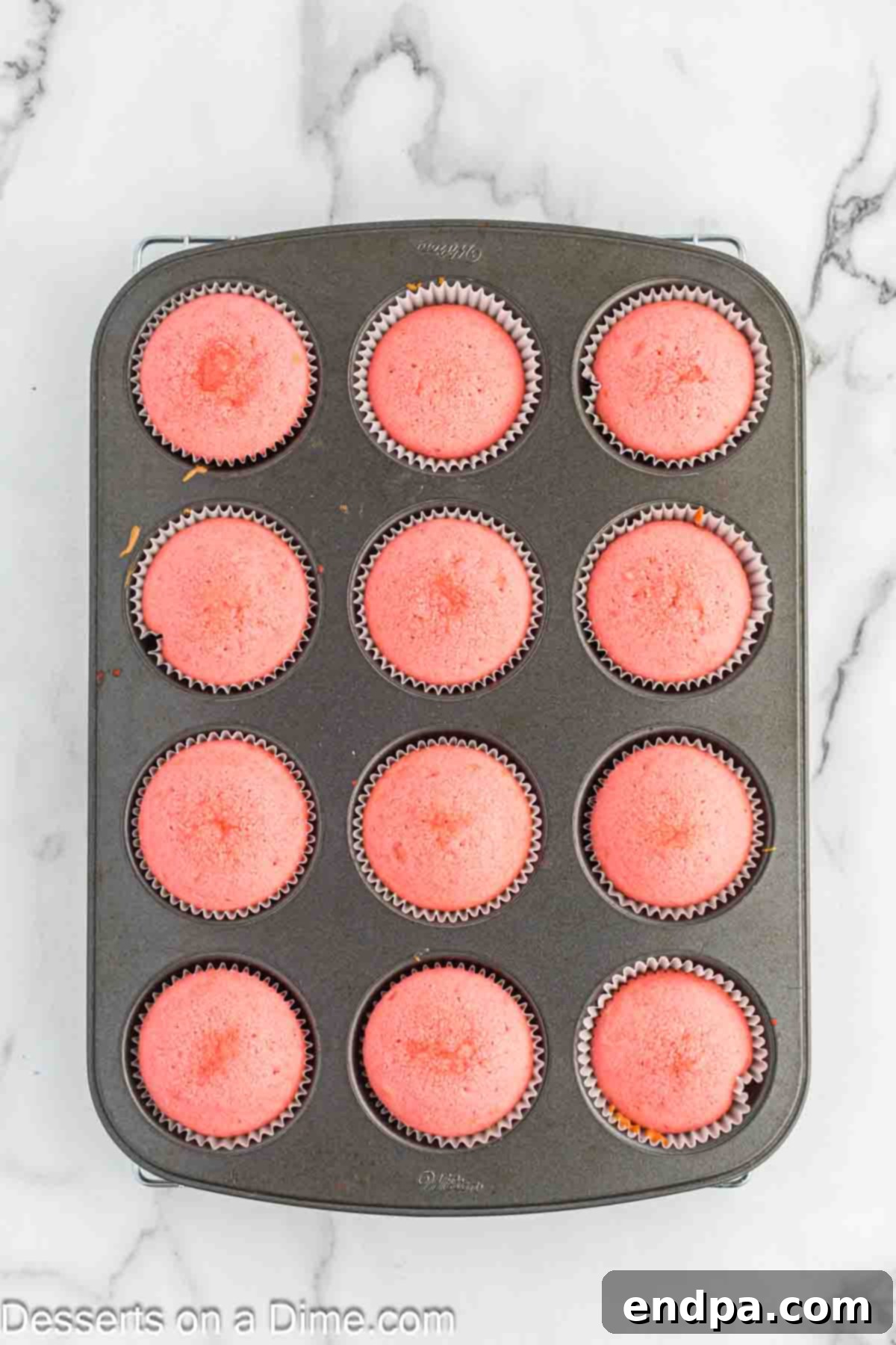 Baked cupcakes cooling in a muffin tin, fresh out of the oven.