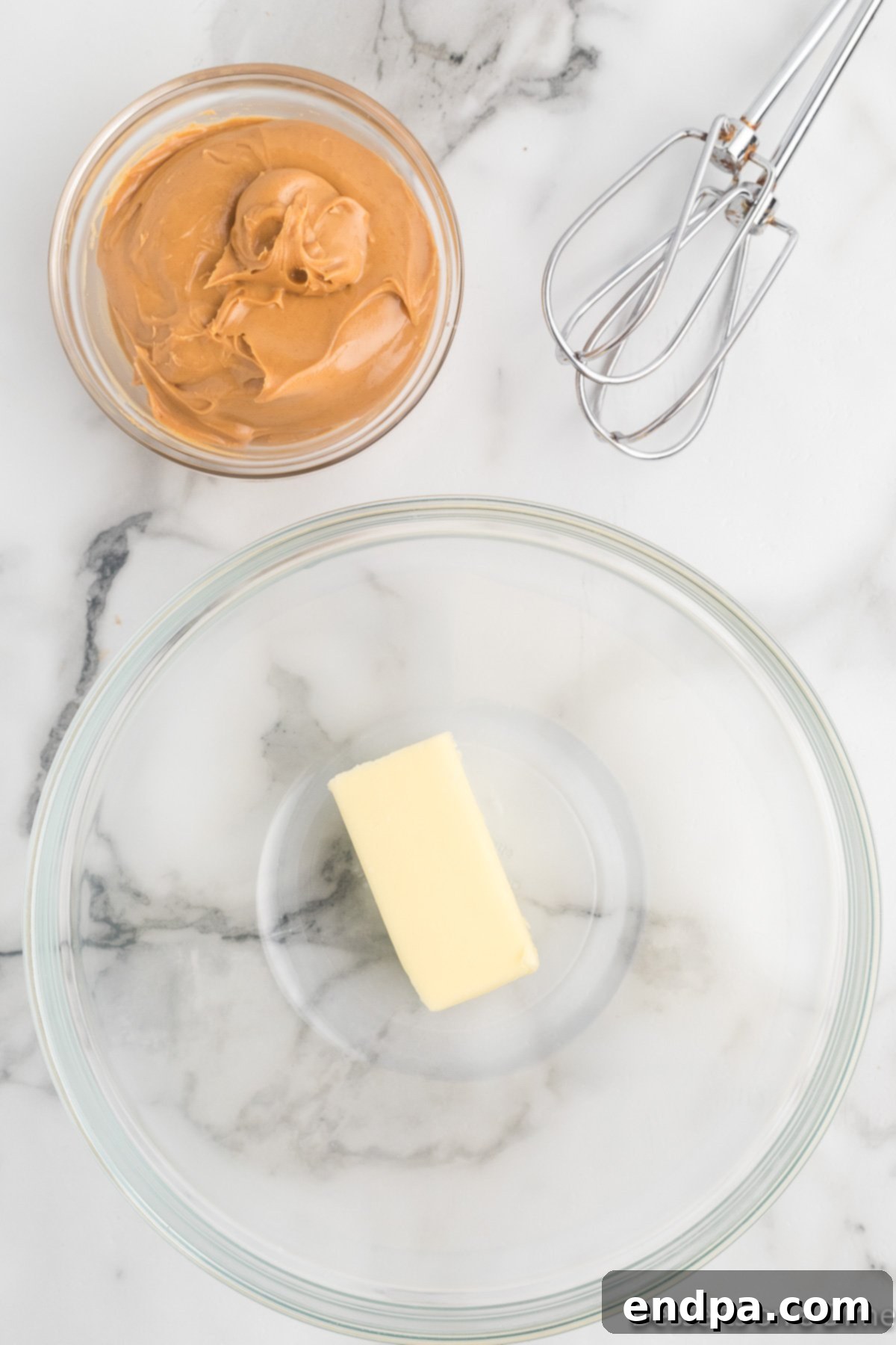 Softened butter in a mixing bowl next to a spoonful of creamy peanut butter, ready to be combined.