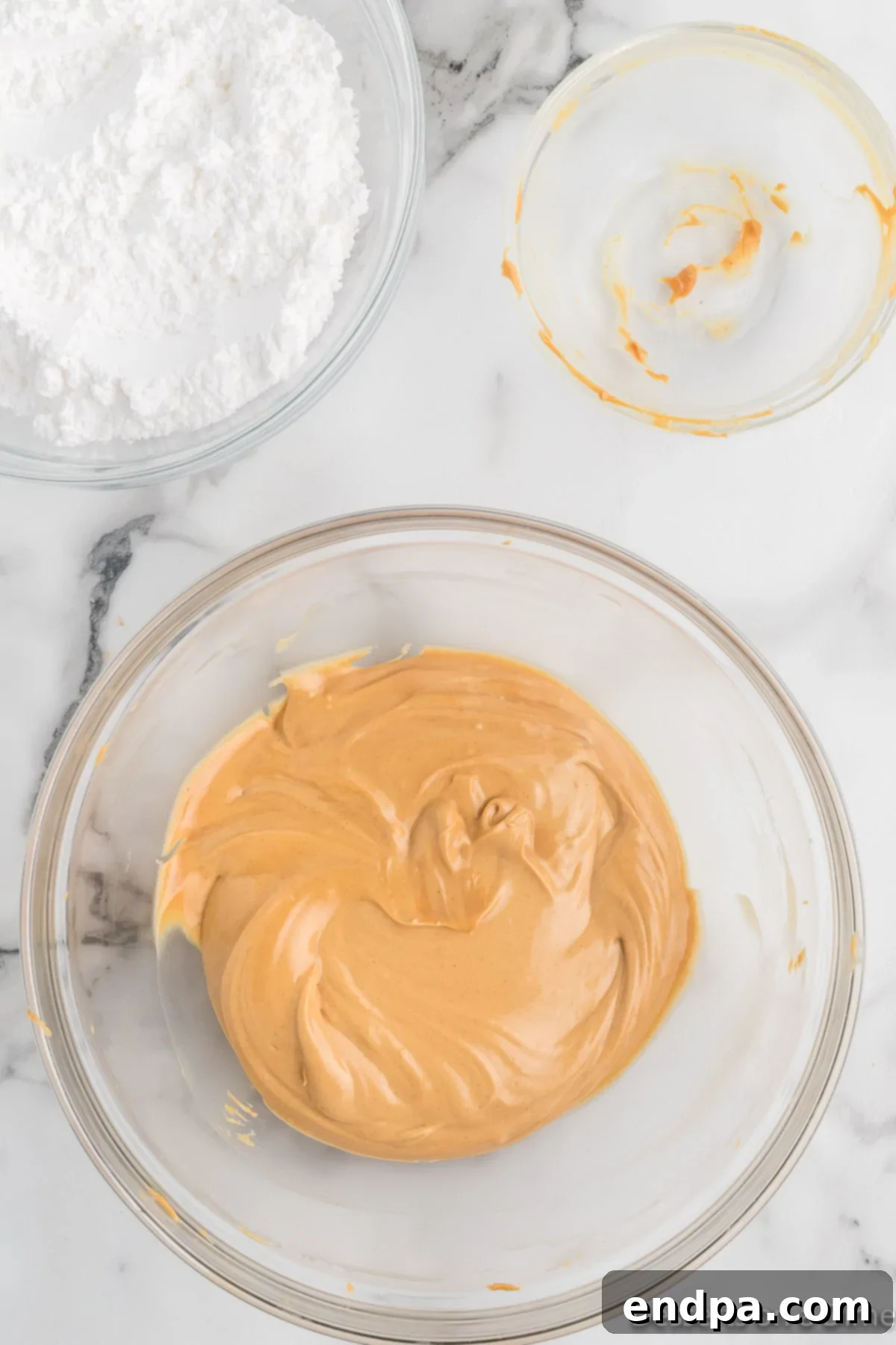 A mixing bowl showing creamy peanut butter and butter thoroughly combined into a smooth, light mixture.