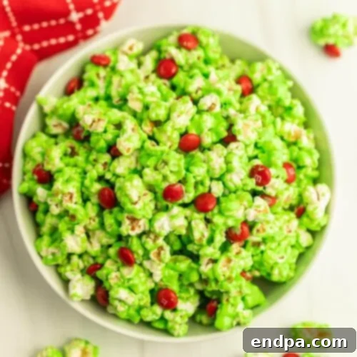 Sweet and salty Grinch Popcorn with green popcorn and red M&M's.