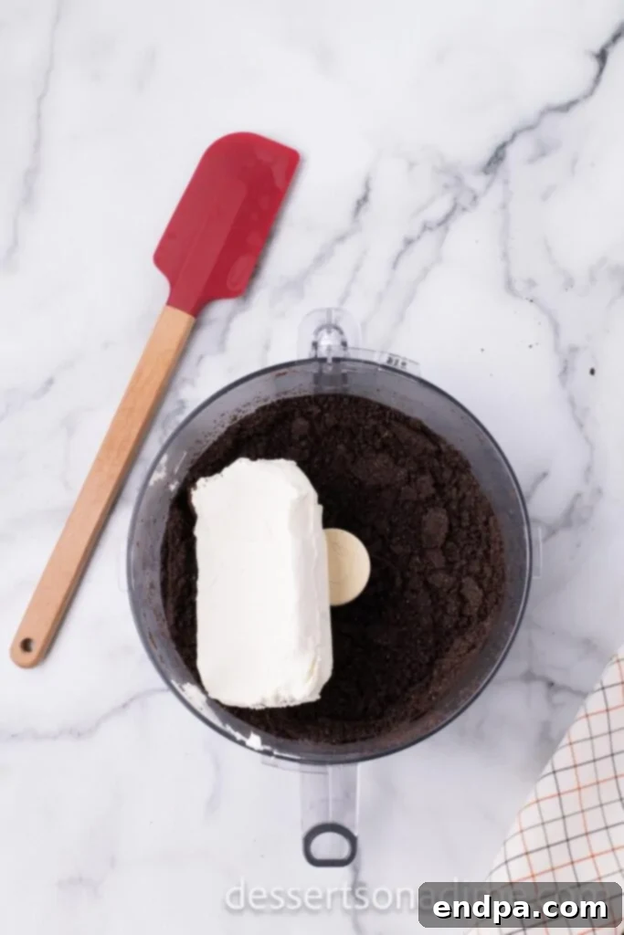 Softened cream cheese added to the food processor with crushed Oreos.