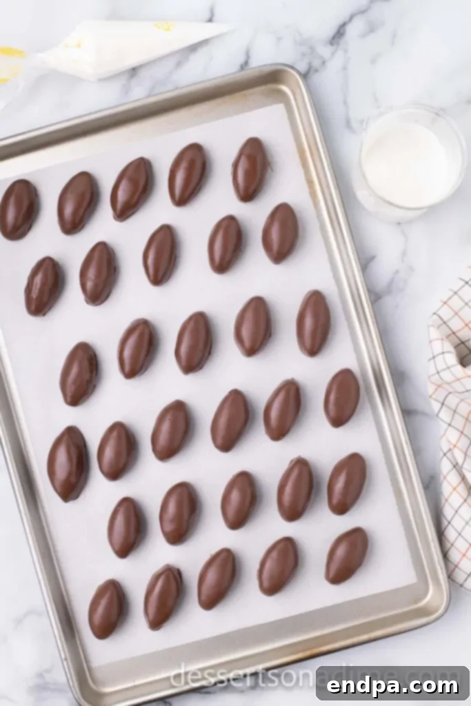 Chocolate-coated football shaped Oreo balls arranged on wax paper.