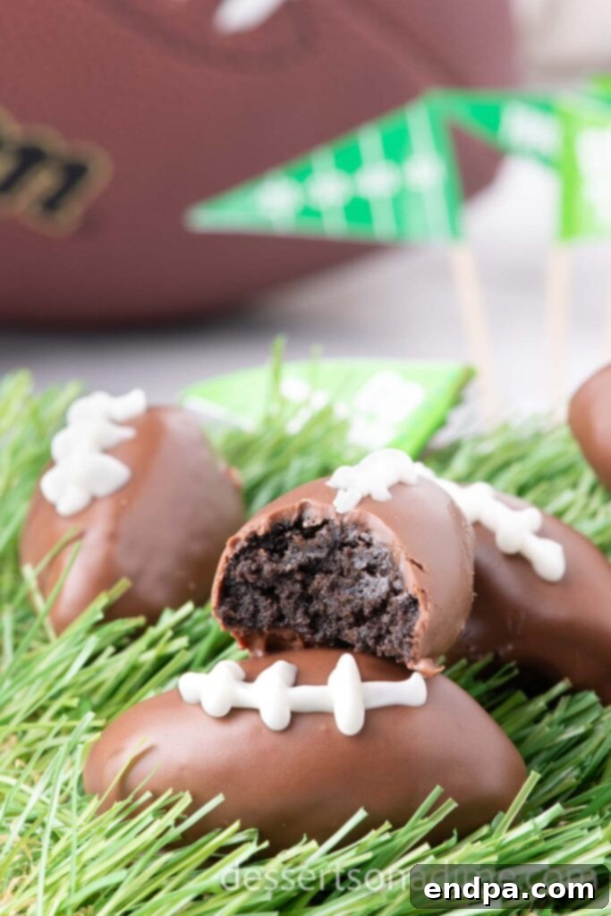 Festive Football Shaped Oreo Balls on faux grass, some cut in half to show the inside.