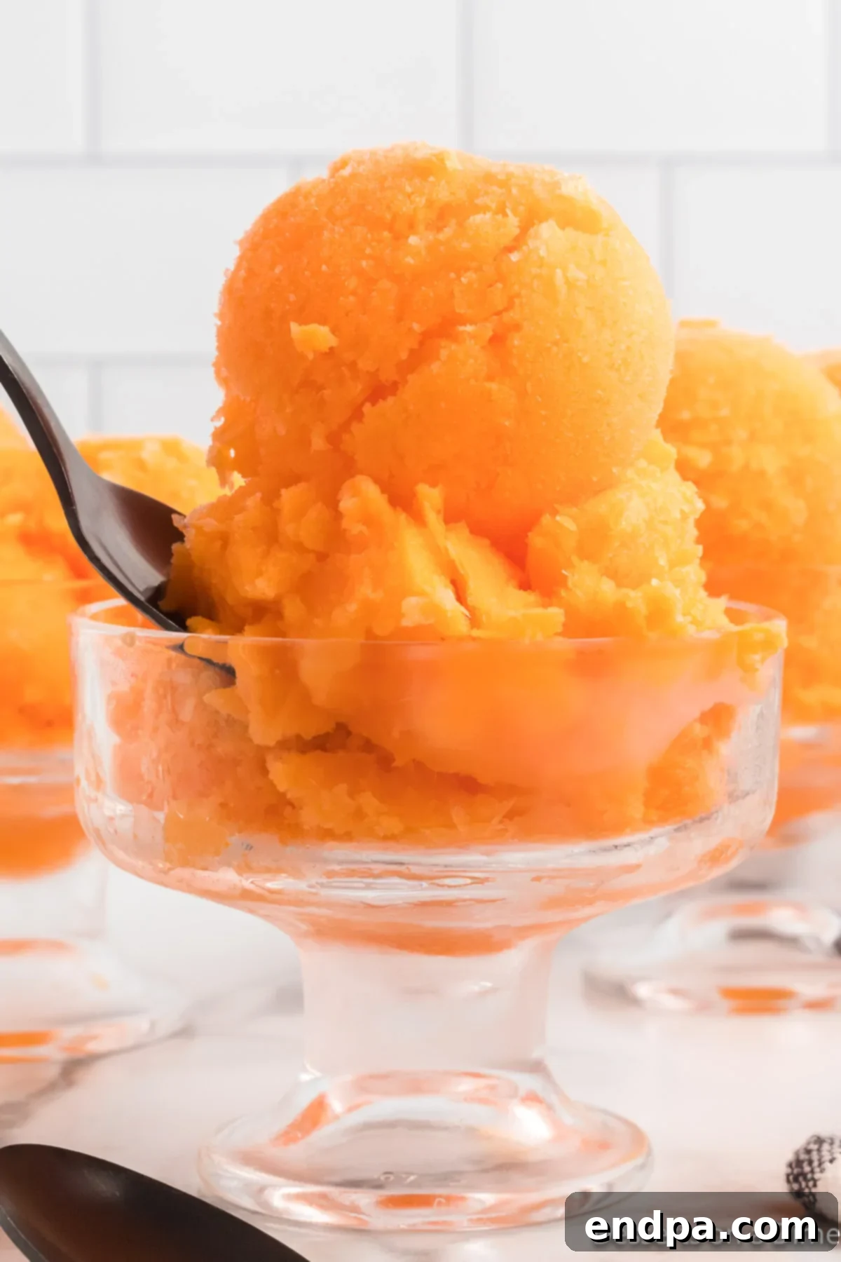 Sunset Swirl 8 Close-up of creamy orange sherbet scoops in a glass dish, highlighting its smooth texture.