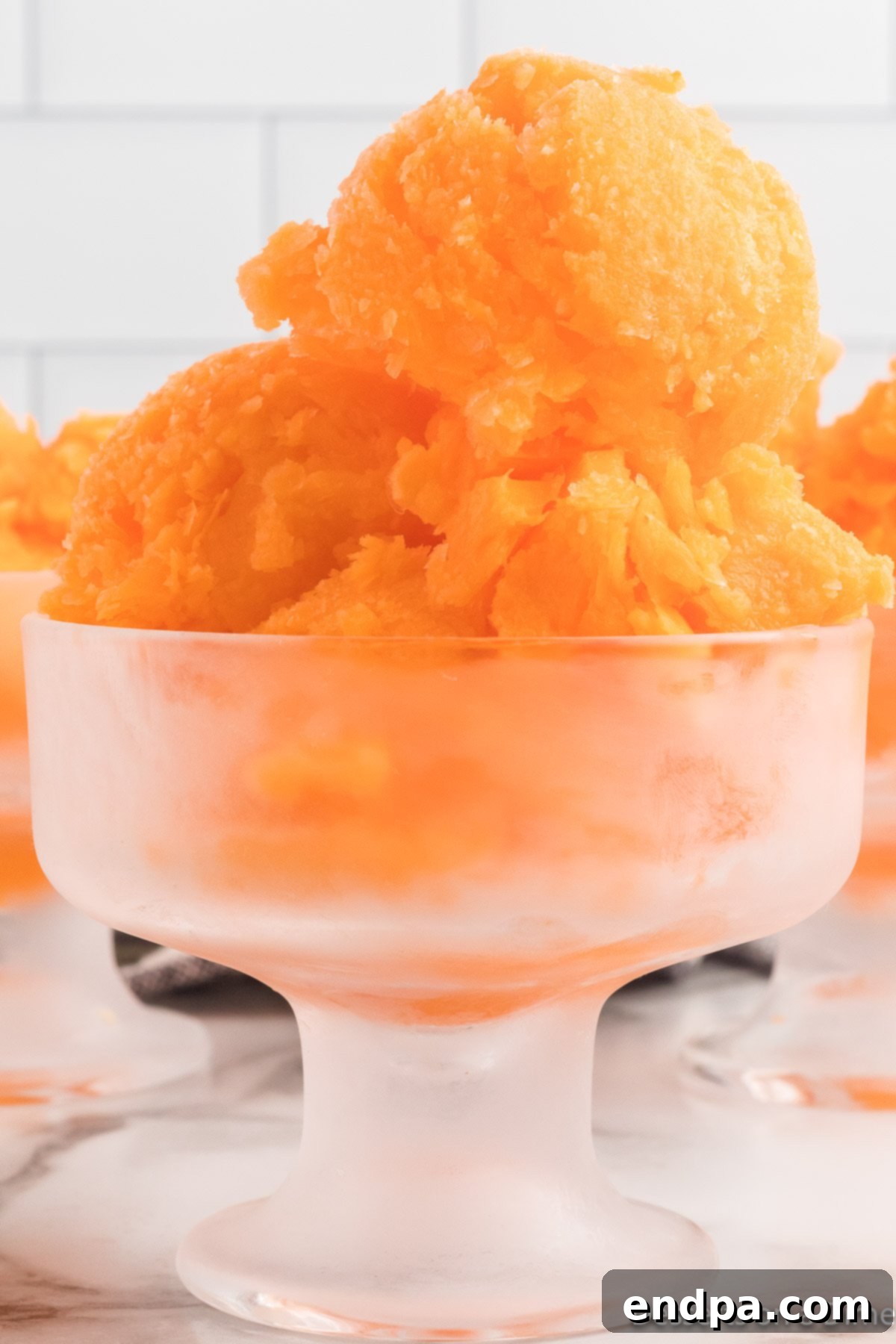 Sunset Swirl 9 Close-up of a serving of orange sherbet, showing its smooth, scoopable consistency.