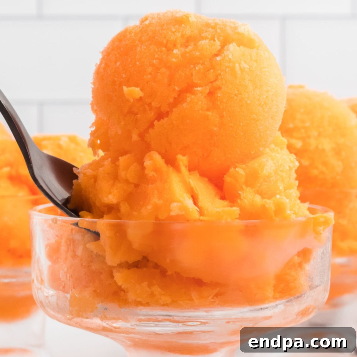 Sunset Swirl 10 A spoon is holding a scoop of orange ice cream, showing the creamy texture.