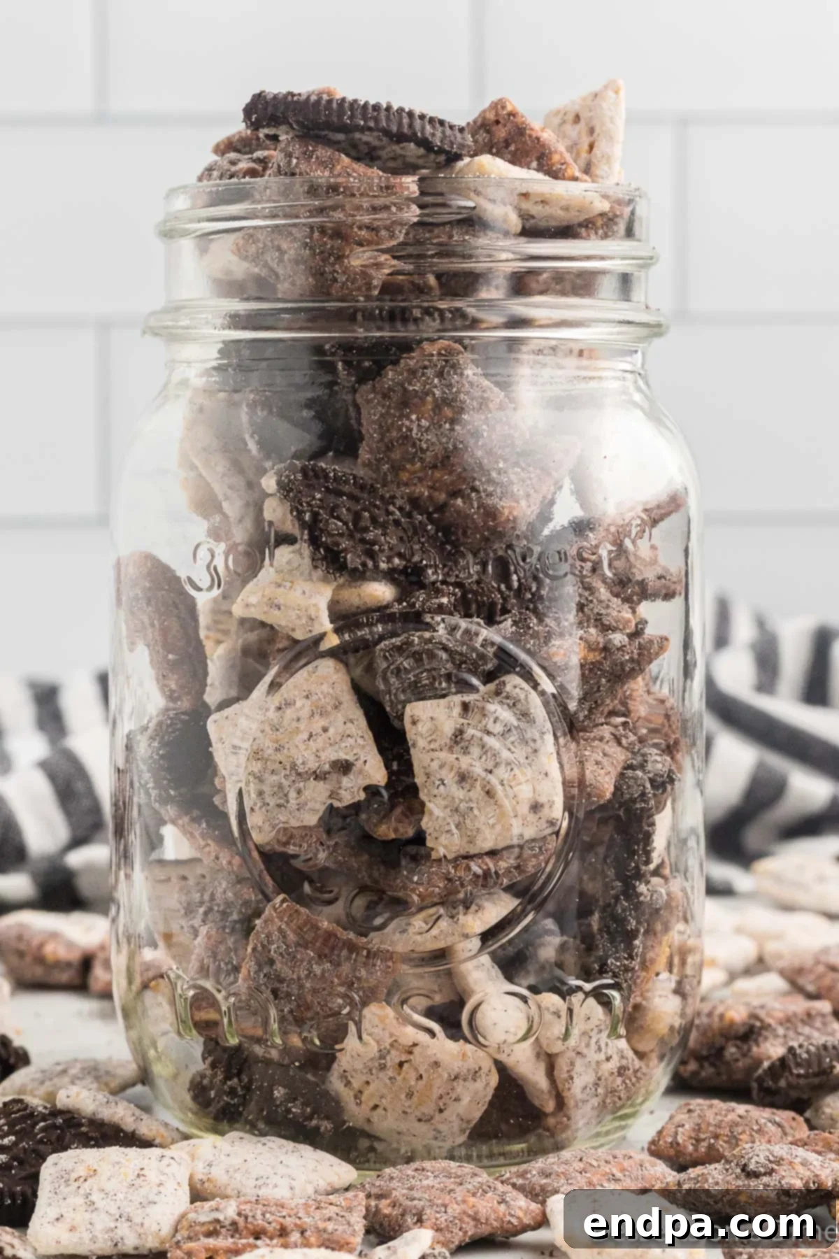 Cookies and Cream Muddy Buddies presented beautifully in a glass jar, ready for serving or gifting.