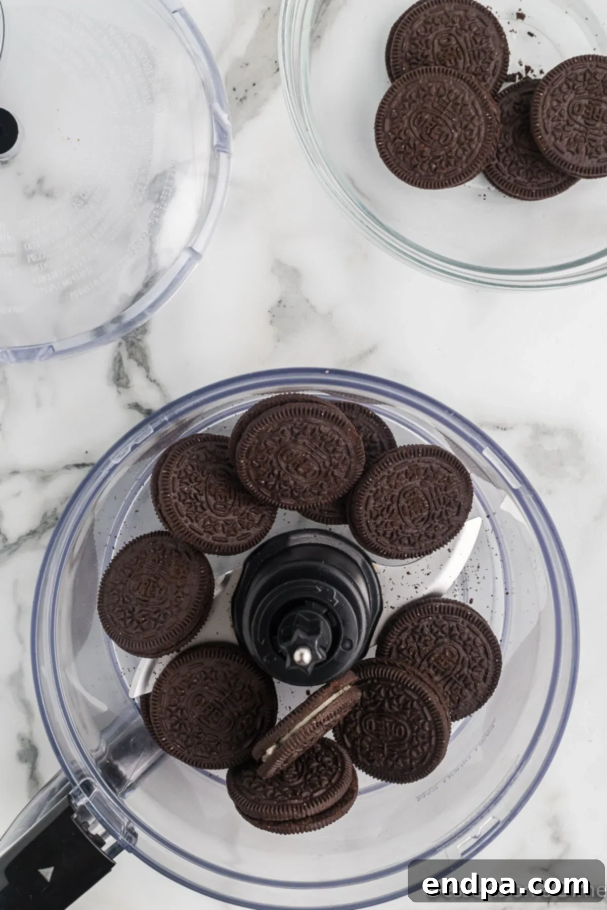 Oreo cookies being crushed in a food processor to fine crumbs.
