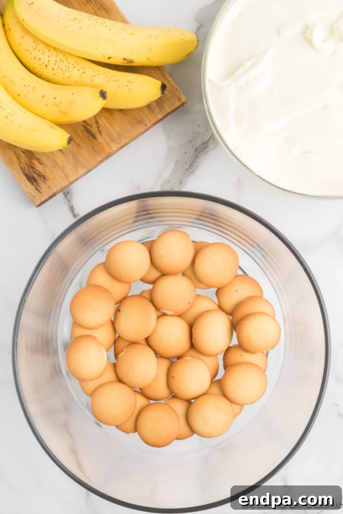 Homemade Magnolia Bakery Banana Pudding Perfection 7 Glass serving dish with the first layer of vanilla wafers arranged at the bottom.
