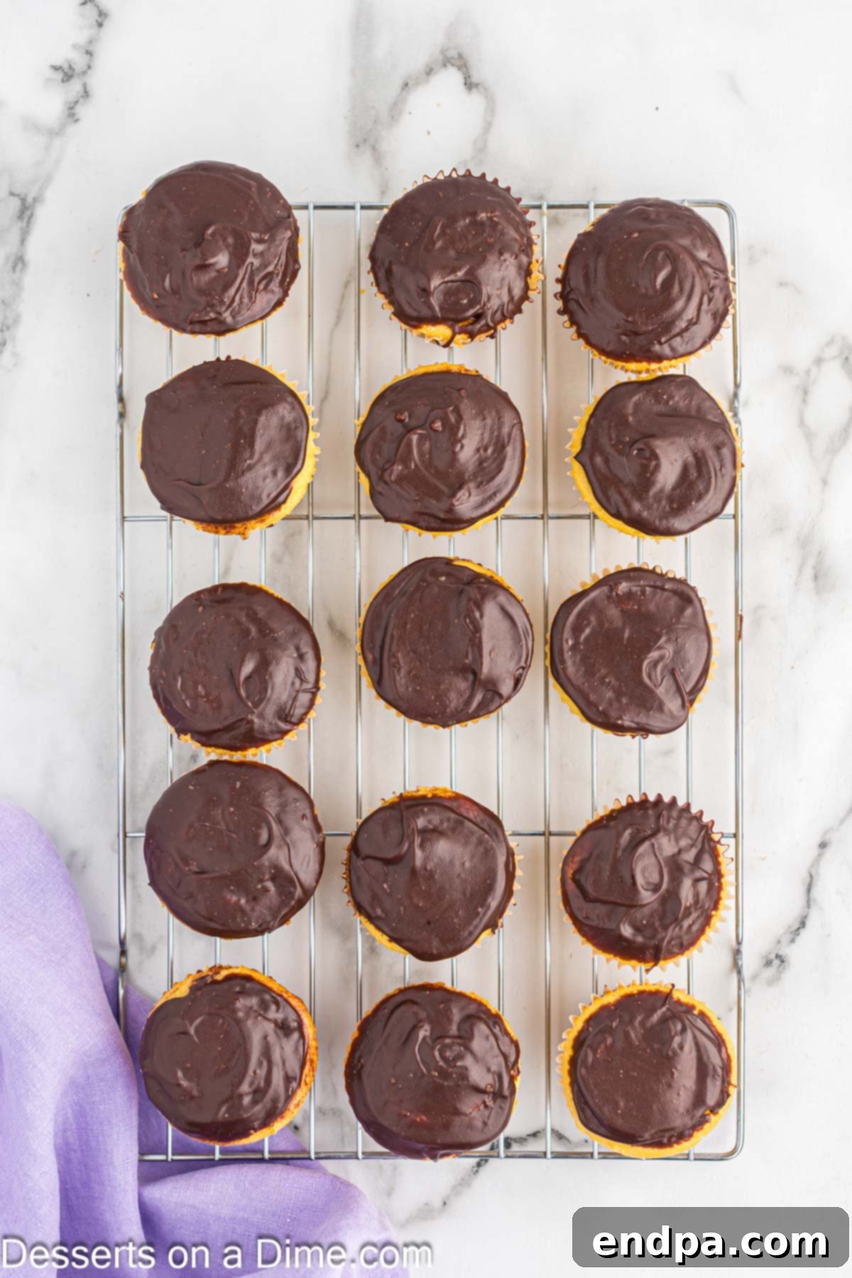 Gourmet Eclair Cupcakes 11 A wire rack filled with beautifully topped Chocolate Eclair Cupcakes, their ganache glistening and ready for serving.