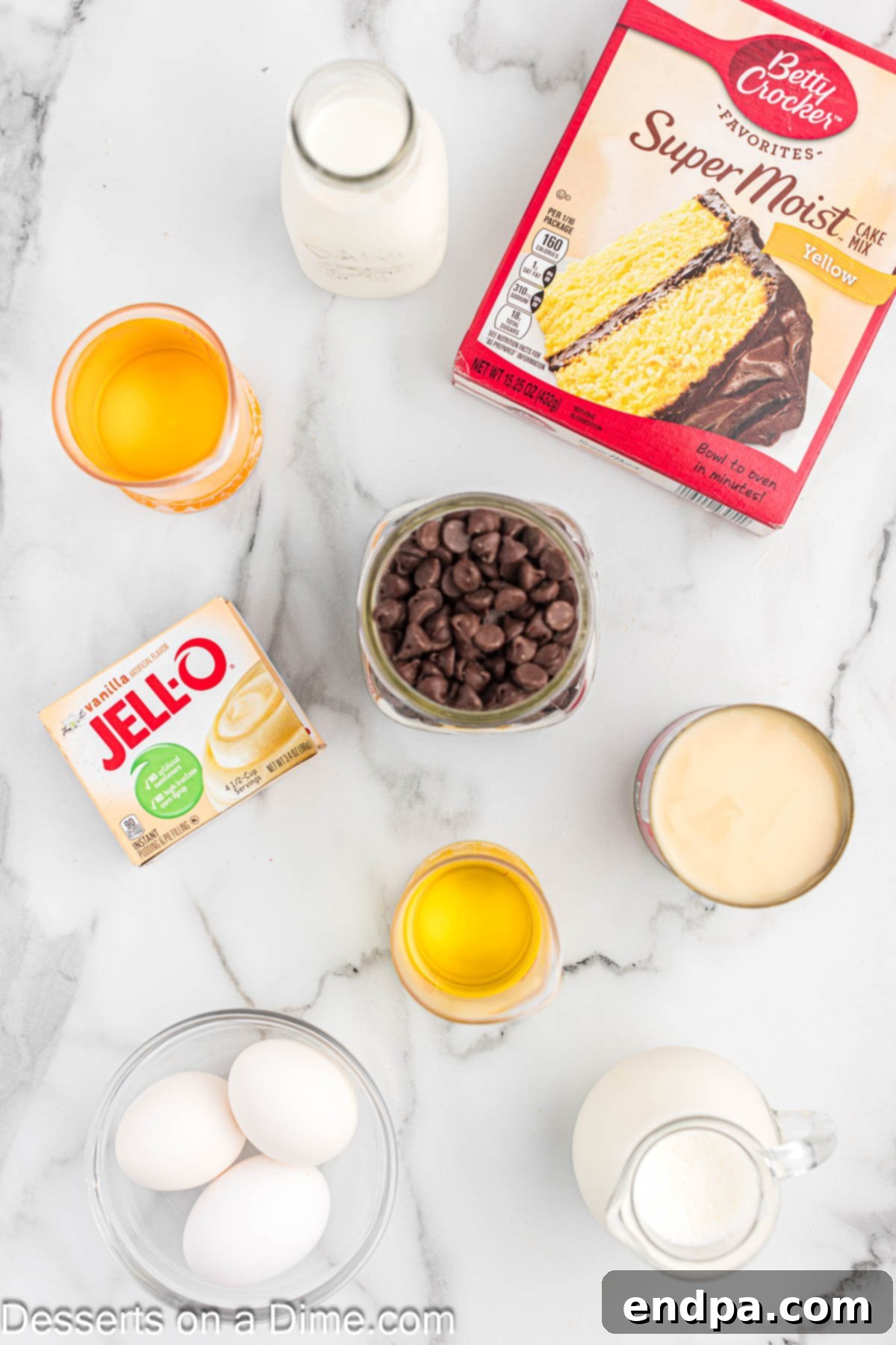 Gourmet Eclair Cupcakes 3 A collection of ingredients for eclair cupcakes laid out on a clean surface. Includes a box of yellow cake mix, oil, eggs, instant pudding mix, sweetened condensed milk, and heavy cream.