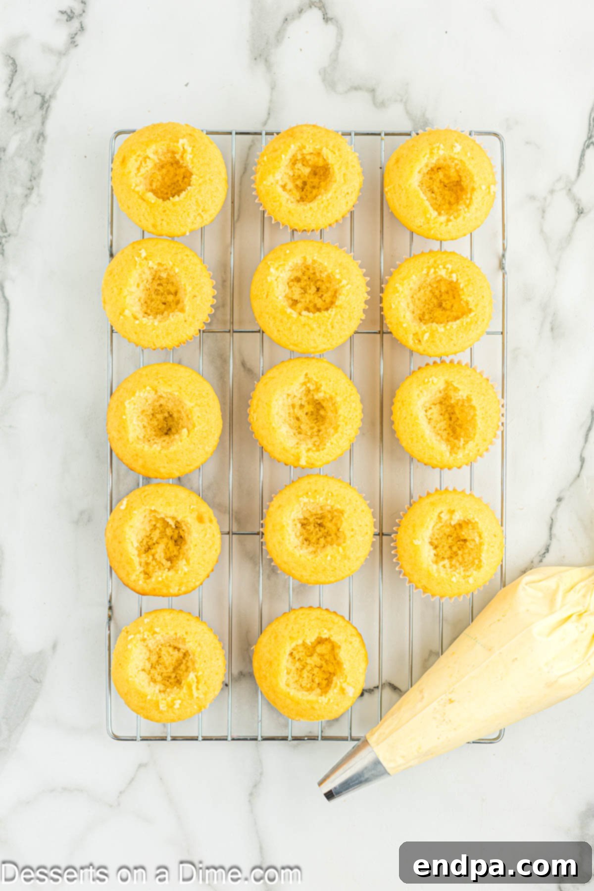 Gourmet Eclair Cupcakes 7 Freshly baked cupcakes, with their centers cored out, arranged on a wire rack to cool down completely.