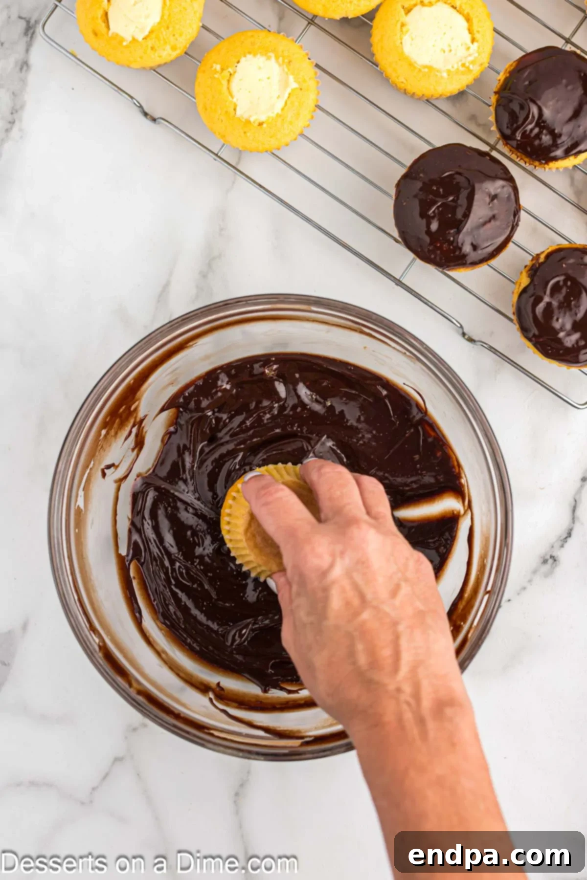 Gourmet Eclair Cupcakes 10 A filled cupcake being carefully inverted and dipped into a bowl of warm, melted chocolate ganache, creating a smooth, glossy coating.
