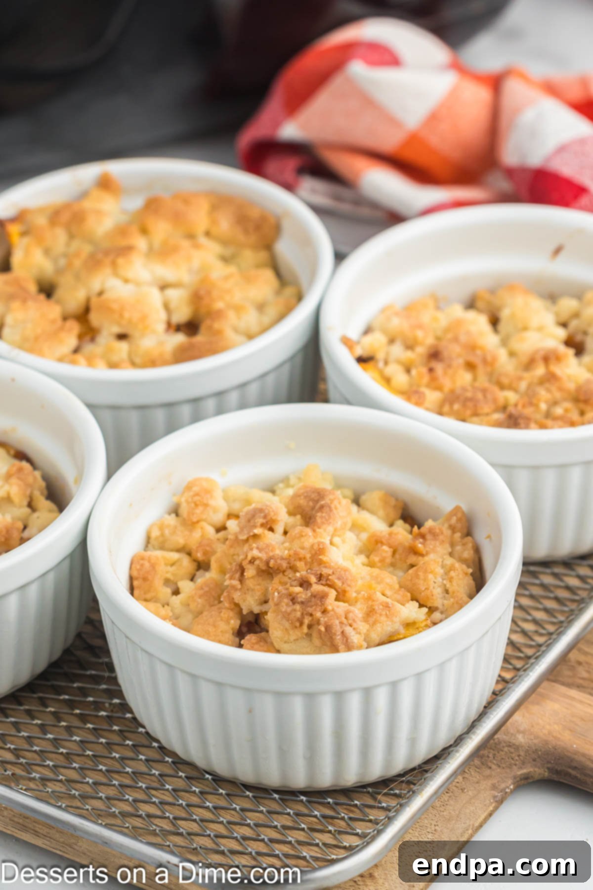 Peach cobbler in ramekins on a wire platter, ready to serve