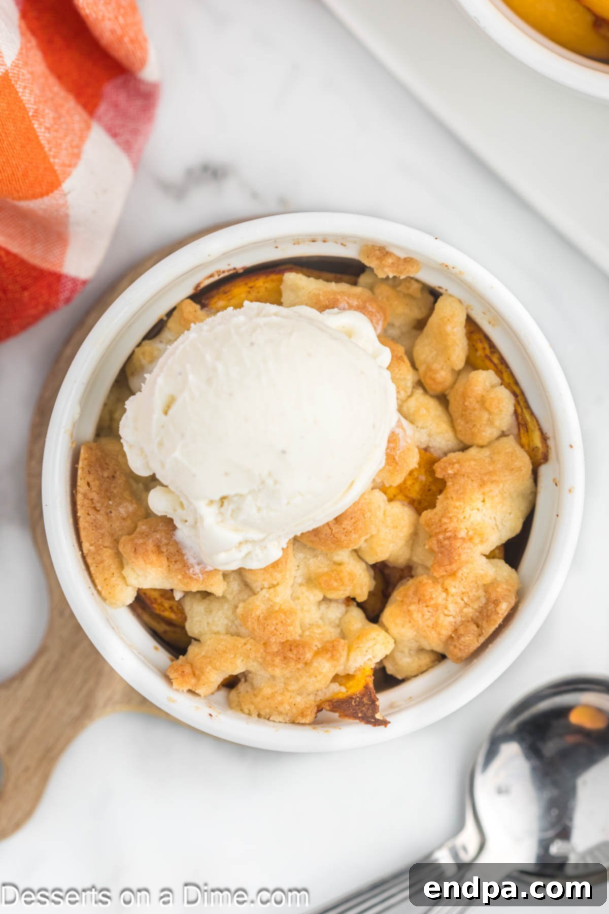 Peach Cobbler in a ramekin with a scoop of vanilla ice cream
