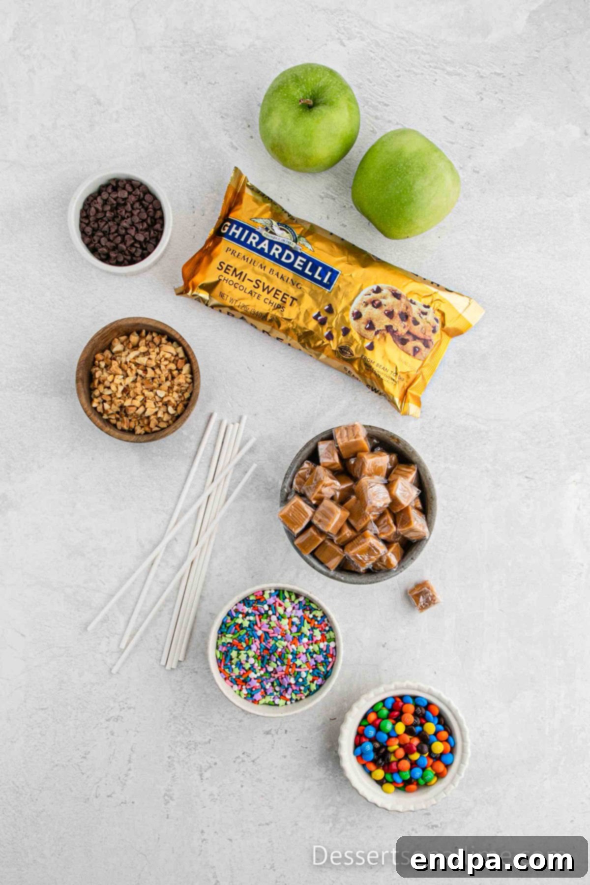 Ingredients for the best caramel apple slices - chocolate chips, caramel, granny smith apples and bowls of toppings.