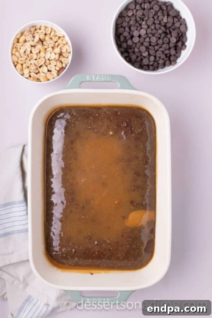 Snickers Overload Cake 7 The partially baked chocolate cake with the warm caramel mixture poured evenly over the top.