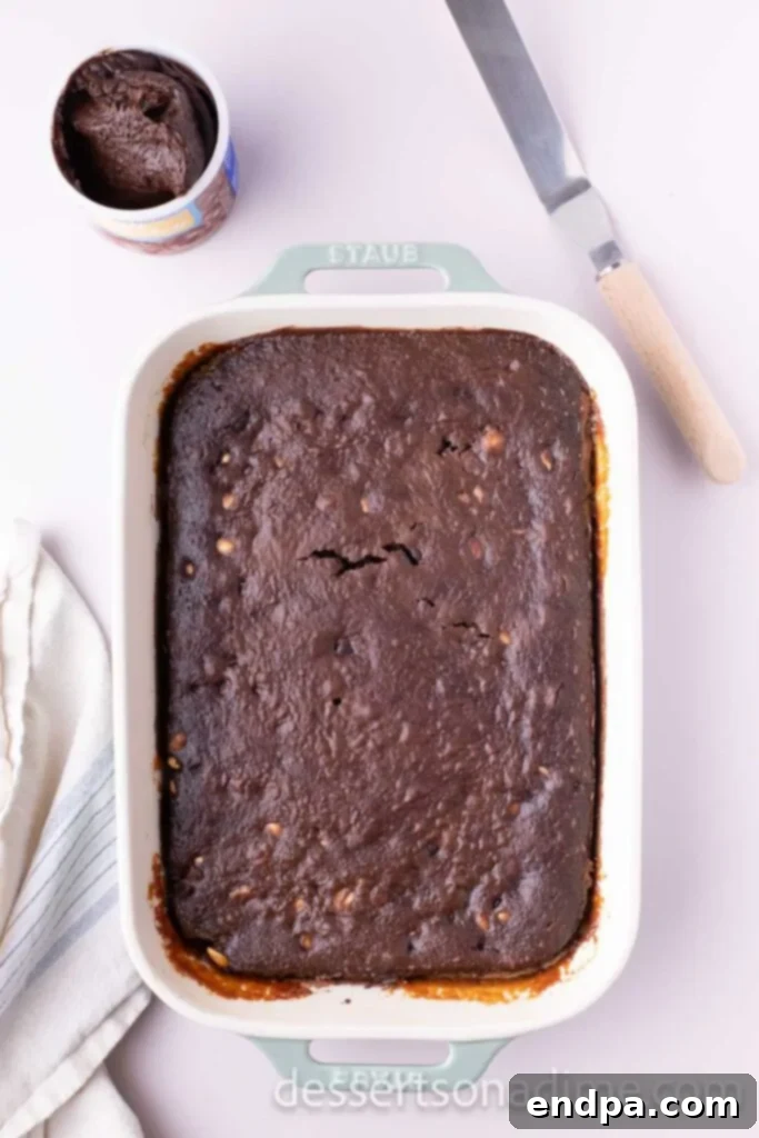 Snickers Overload Cake 9 The remaining cake batter spread over the caramel, chocolate chips, and peanuts, ready for its final bake.