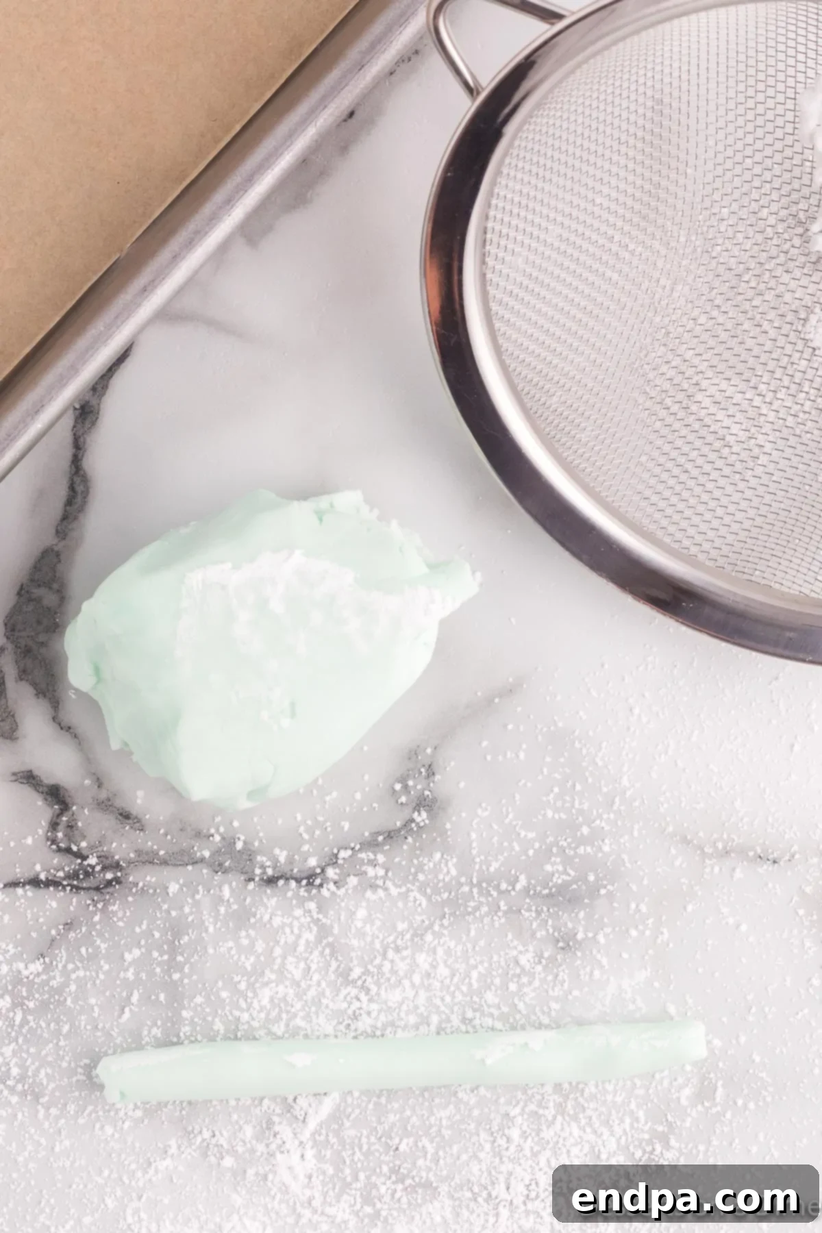Creamy Mint Delights 7 Butter mint dough rolled into a long, thin rope on a powdered sugar-dusted surface, ready to be cut into individual mints.