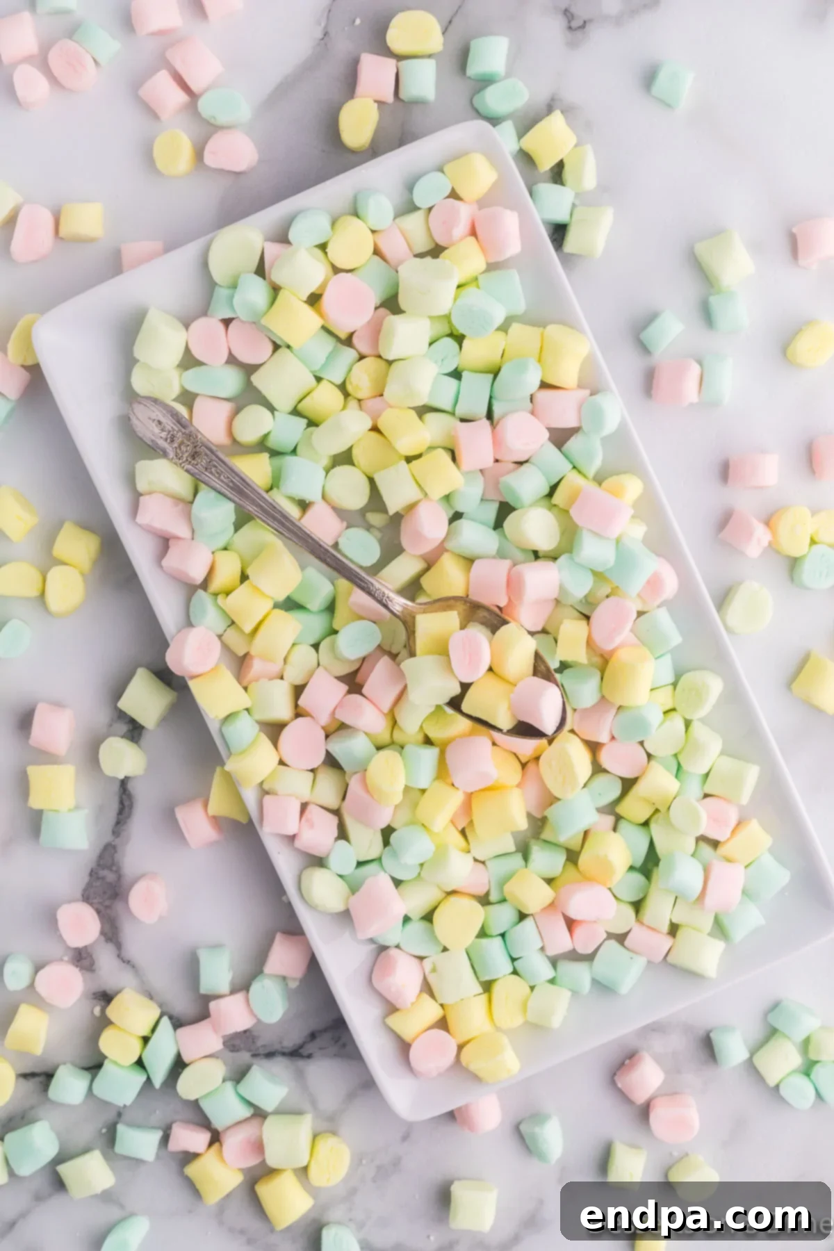 Creamy Mint Delights 10 A decorative tray presenting an assortment of colorful, finished butter mints, along with a small serving spoon.
