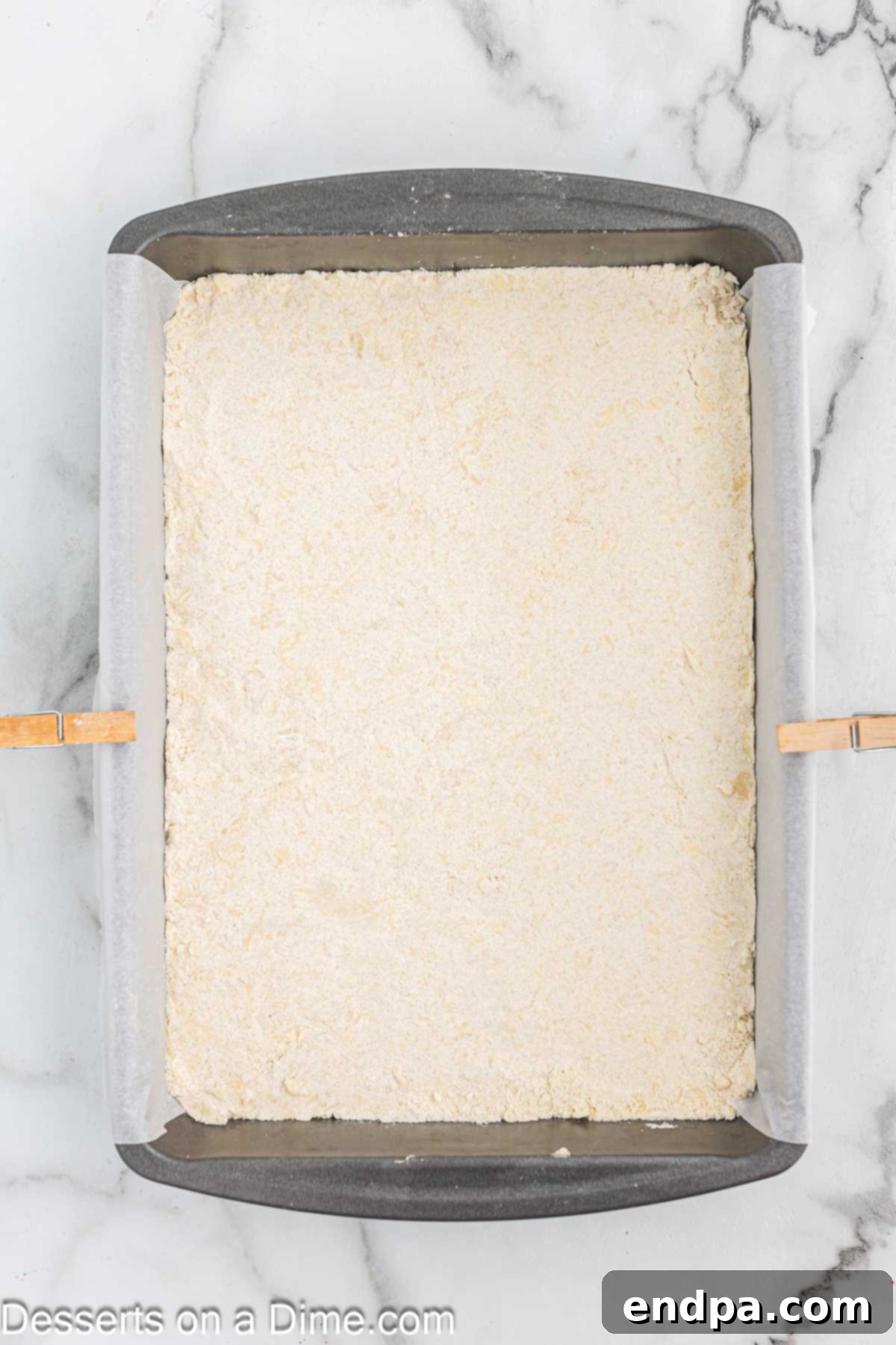The crumbly crust mixture pressed firmly and evenly into the prepared 9x13-inch baking dish, forming a solid base.