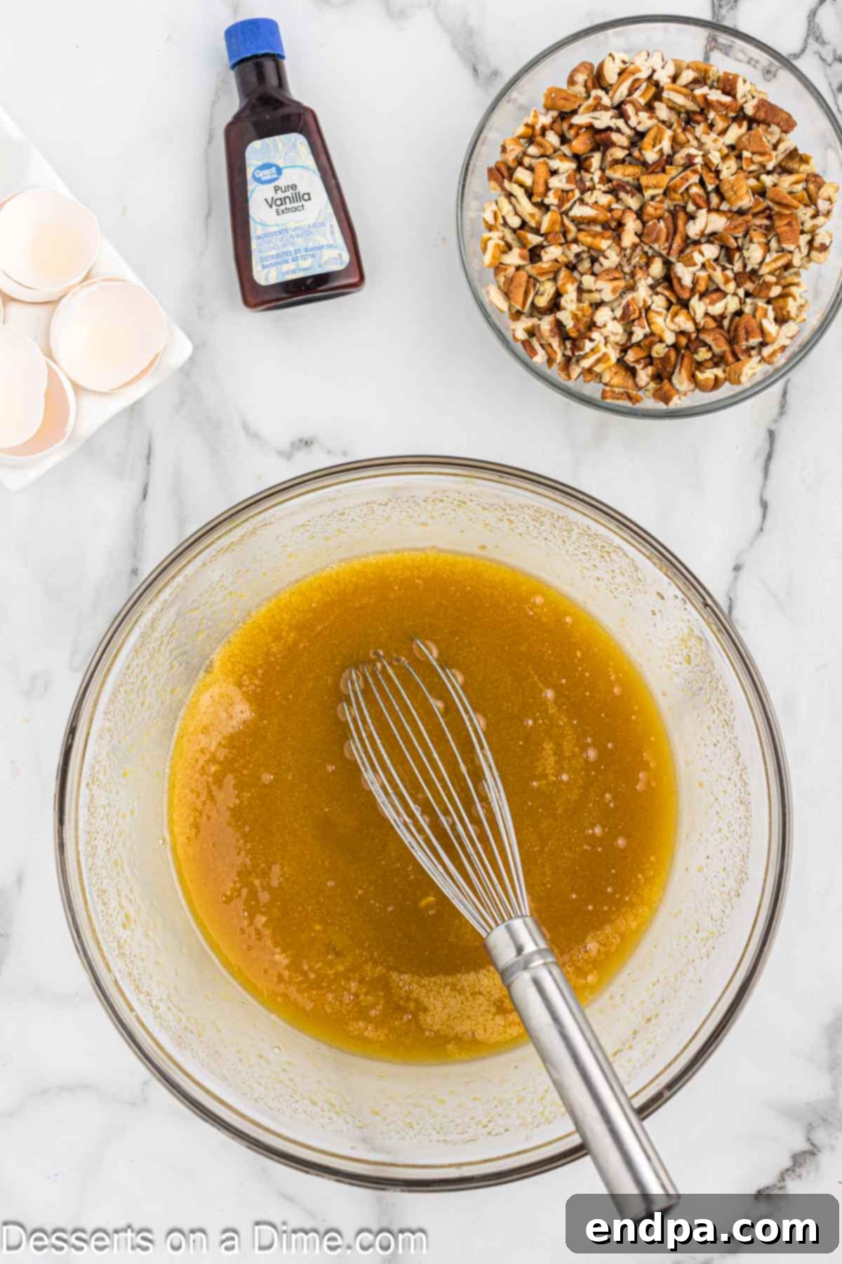 The liquid ingredients for the pecan topping, including brown sugar, corn syrup, eggs, and vanilla, whisked together in a bowl.