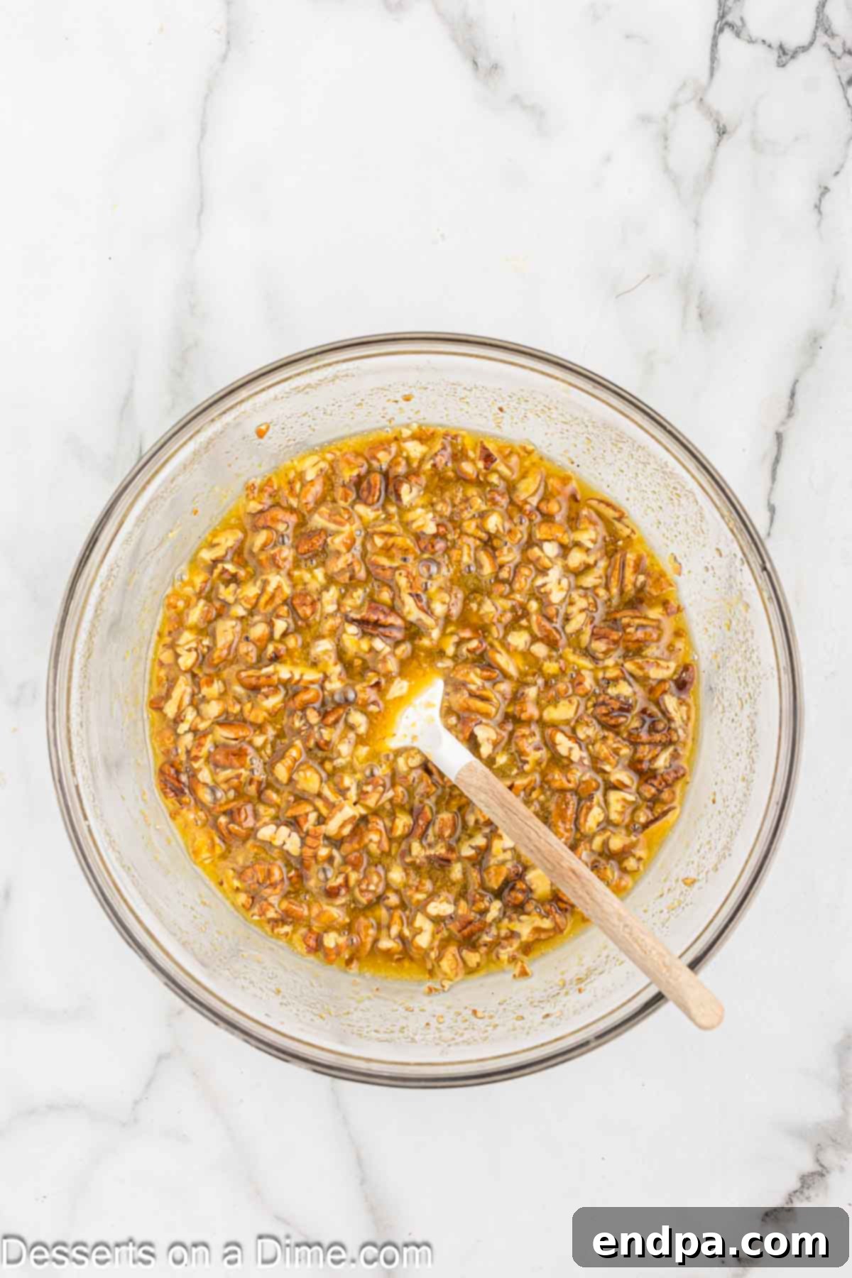 Chopped pecan halves being carefully folded into the prepared sweet and gooey pecan topping mixture.