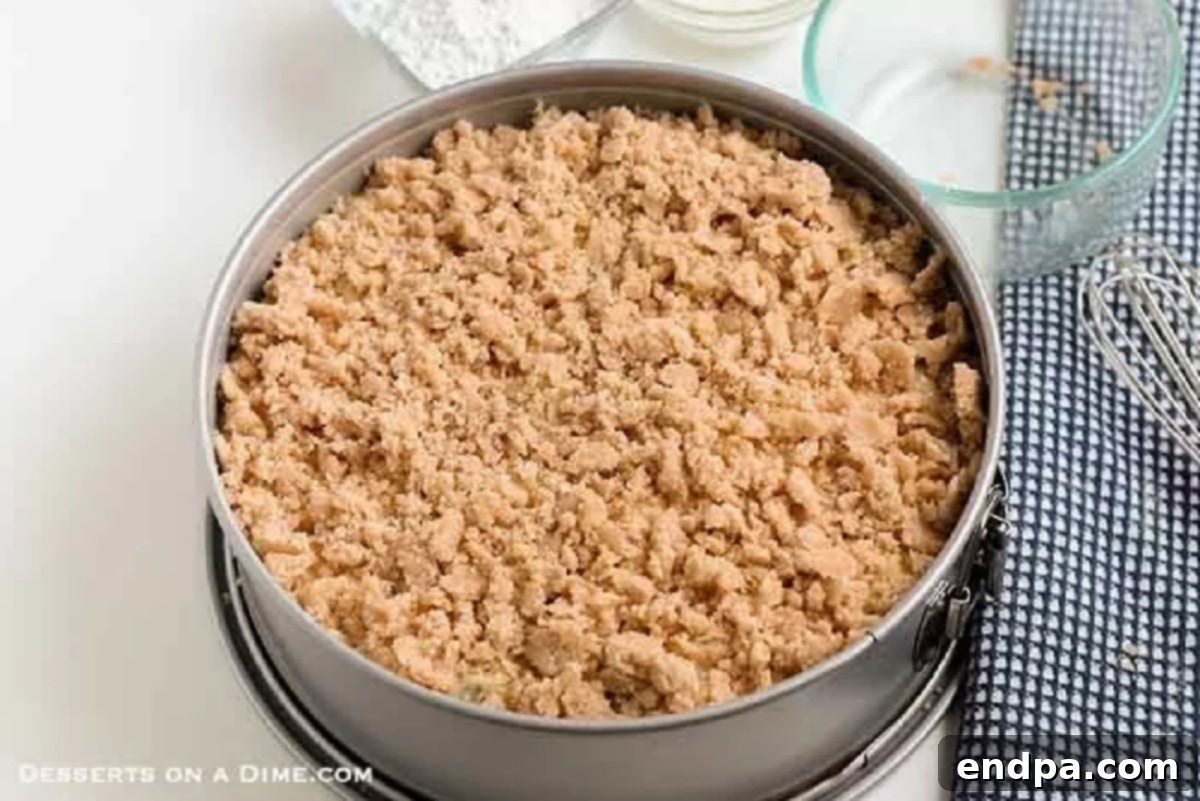 Golden-brown crumb topping generously sprinkled over the surface of the unbaked coffee cake batter in a pan, ready for baking.