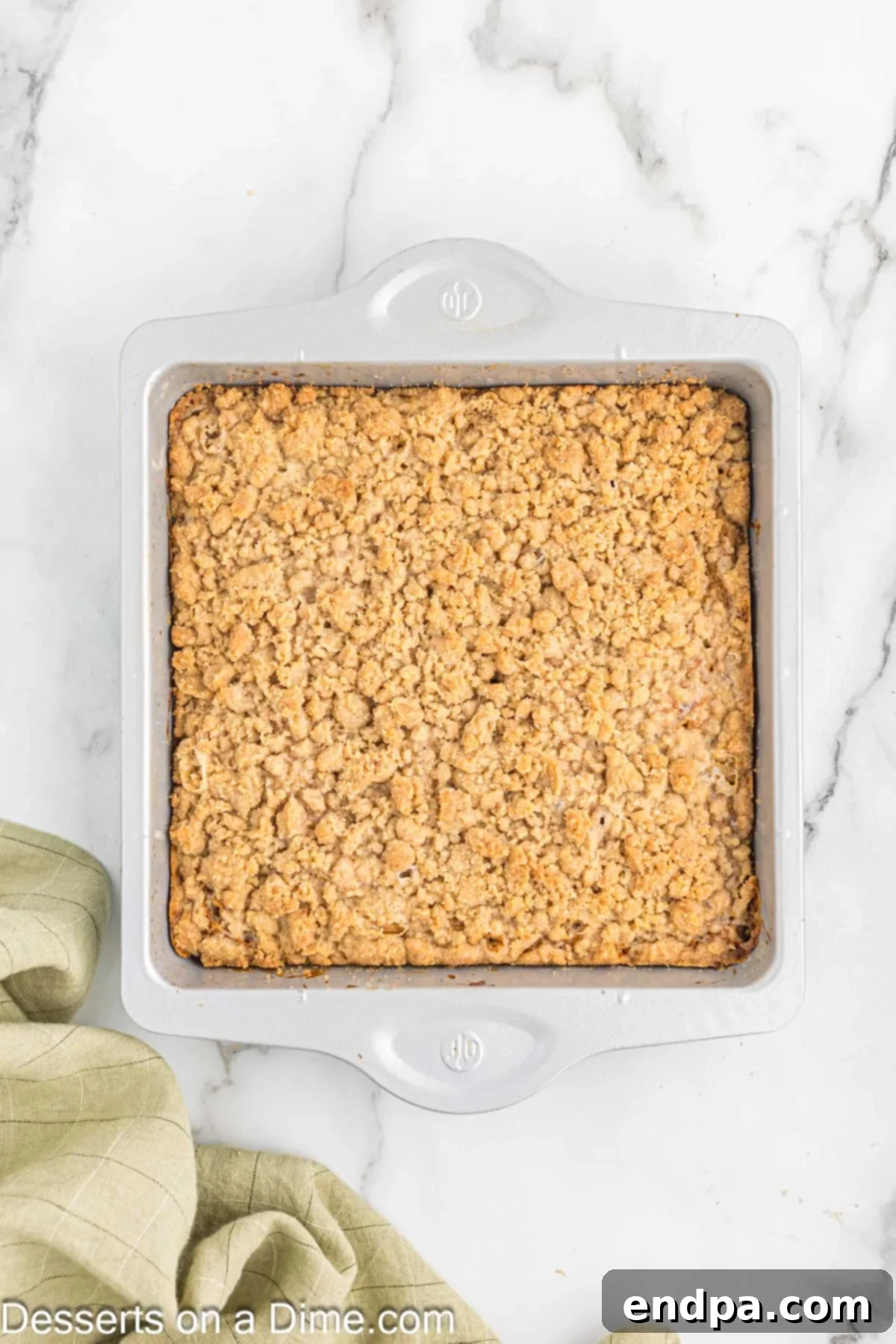 A freshly baked banana coffee cake in its pan, removed from the oven and cooling on a wire rack, with a golden-brown streusel top.