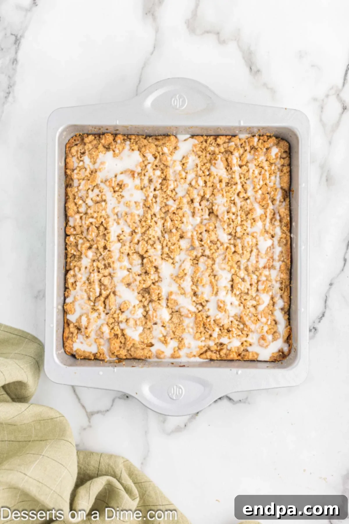 A finished banana coffee cake, generously drizzled with a smooth vanilla glaze, making it look irresistible and ready to serve.