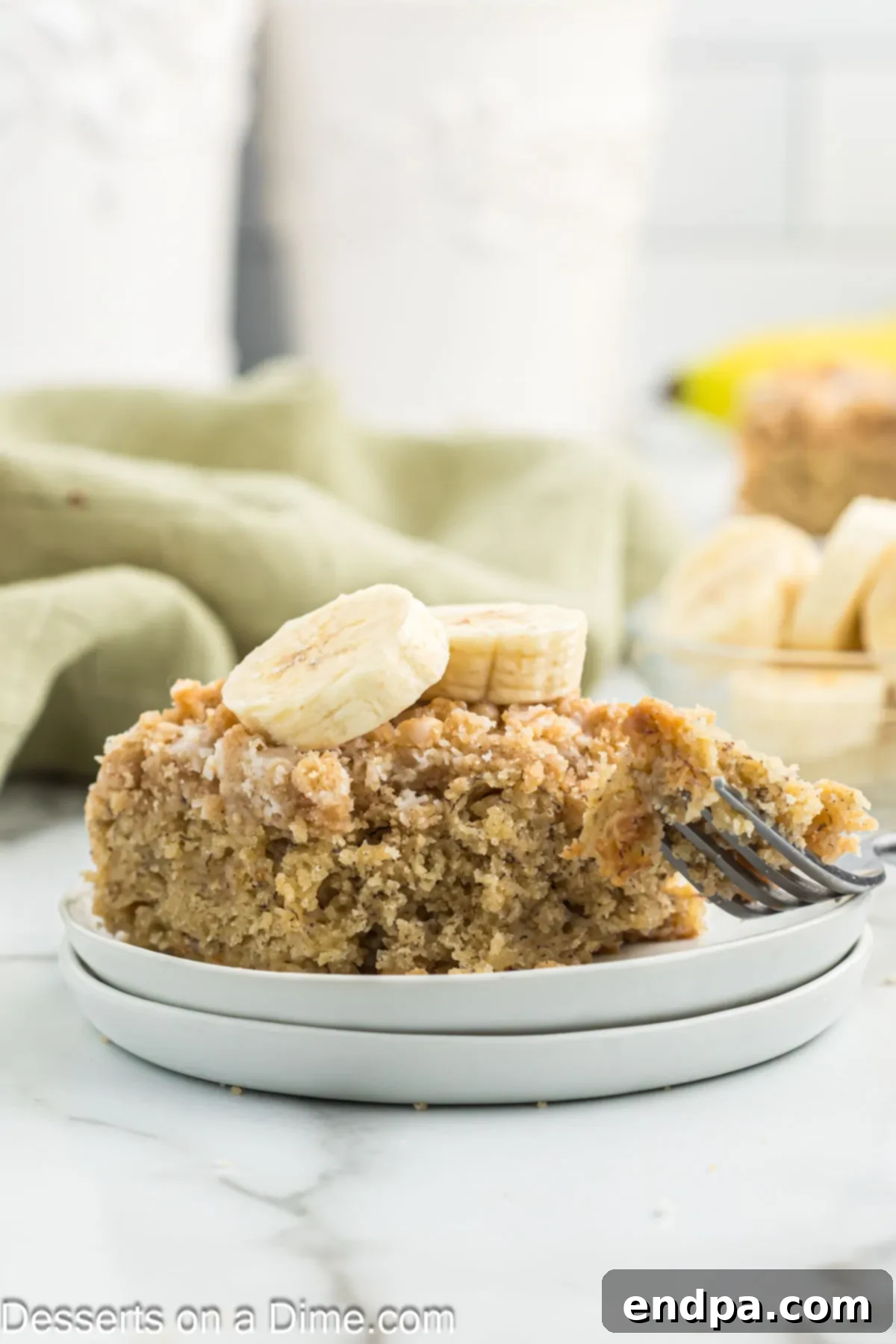 A beautifully sliced piece of banana coffee cake, showcasing its moist, fluffy interior, generous streusel topping, and glossy vanilla glaze.