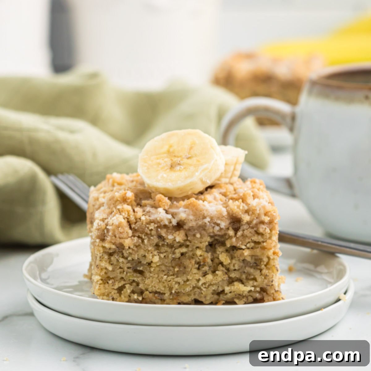 A beautifully presented banana coffee cake, sliced and served, showing off its moist texture, streusel topping, and sweet glaze.