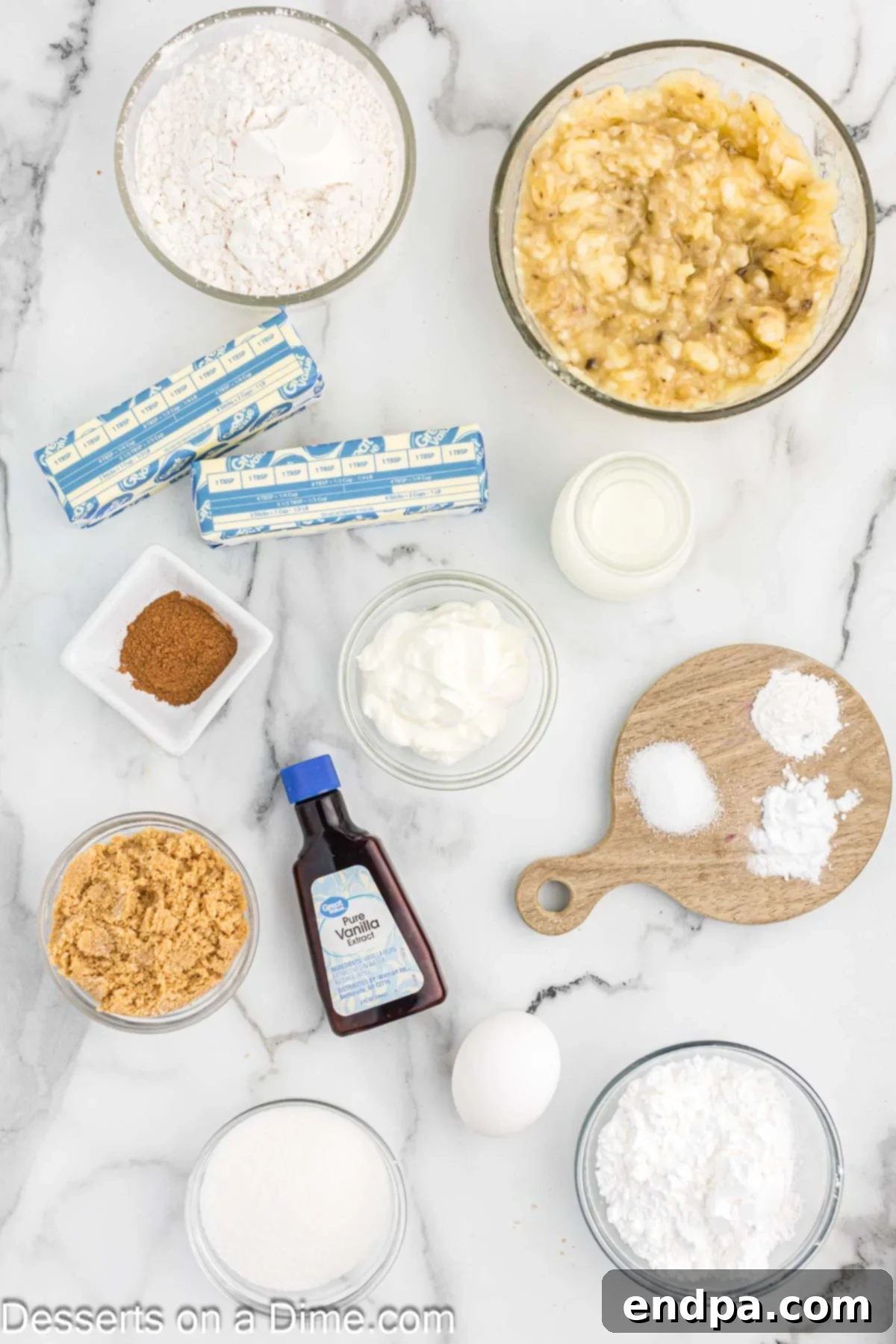 A flat lay photograph displaying the essential ingredients for making banana coffee cake, including measuring cups of all-purpose flour, ripe bananas, softened unsalted butter, vanilla extract, brown sugar, and granulated sugar.