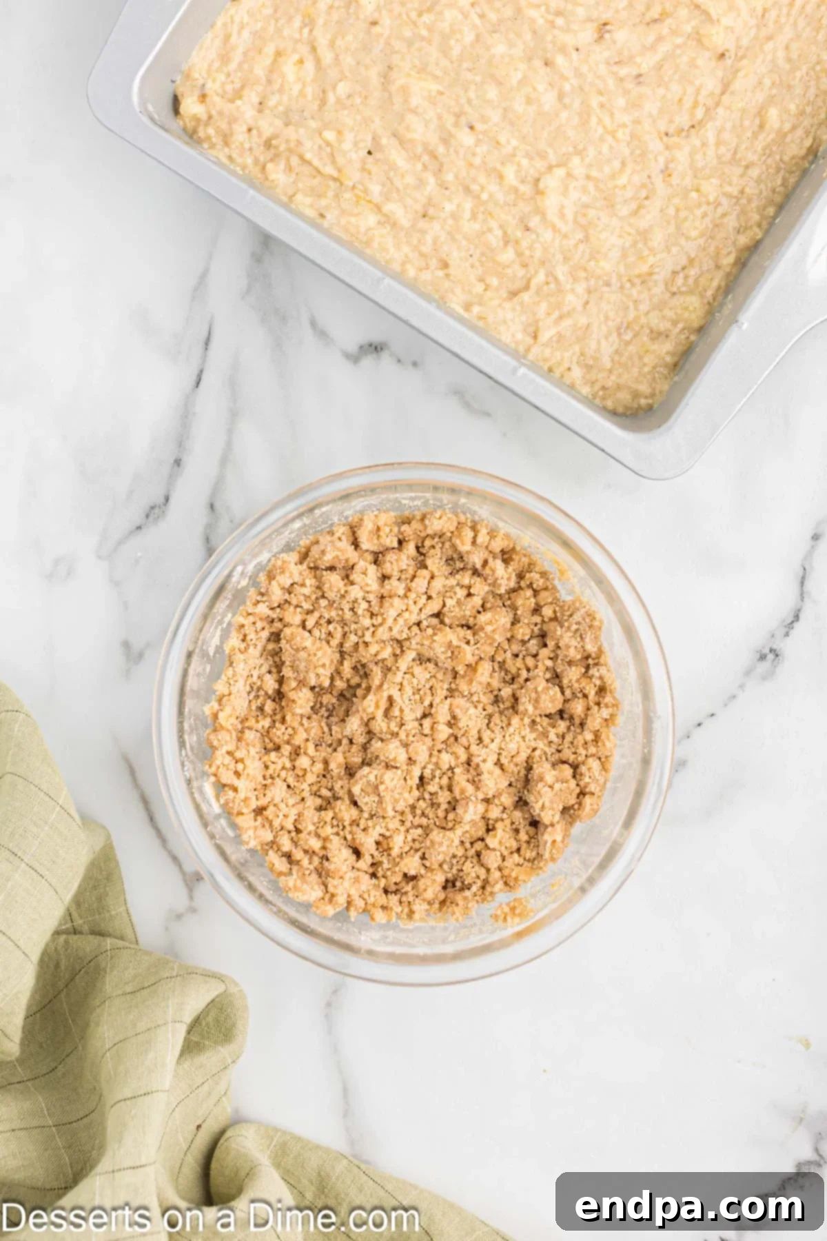 A small bowl containing the crumb topping mixture, showing its coarse texture, ready to be sprinkled over the cake.