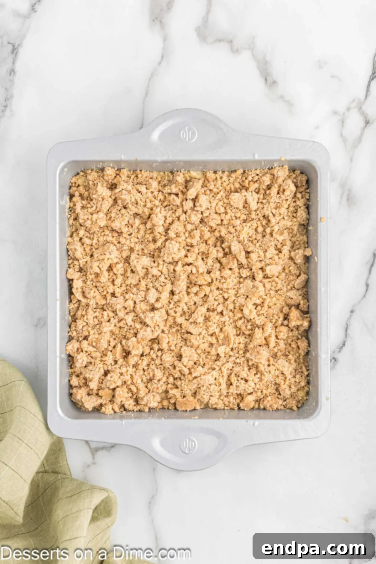 The prepared crumb topping evenly sprinkled over the banana coffee cake batter in the baking pan, covering the surface.