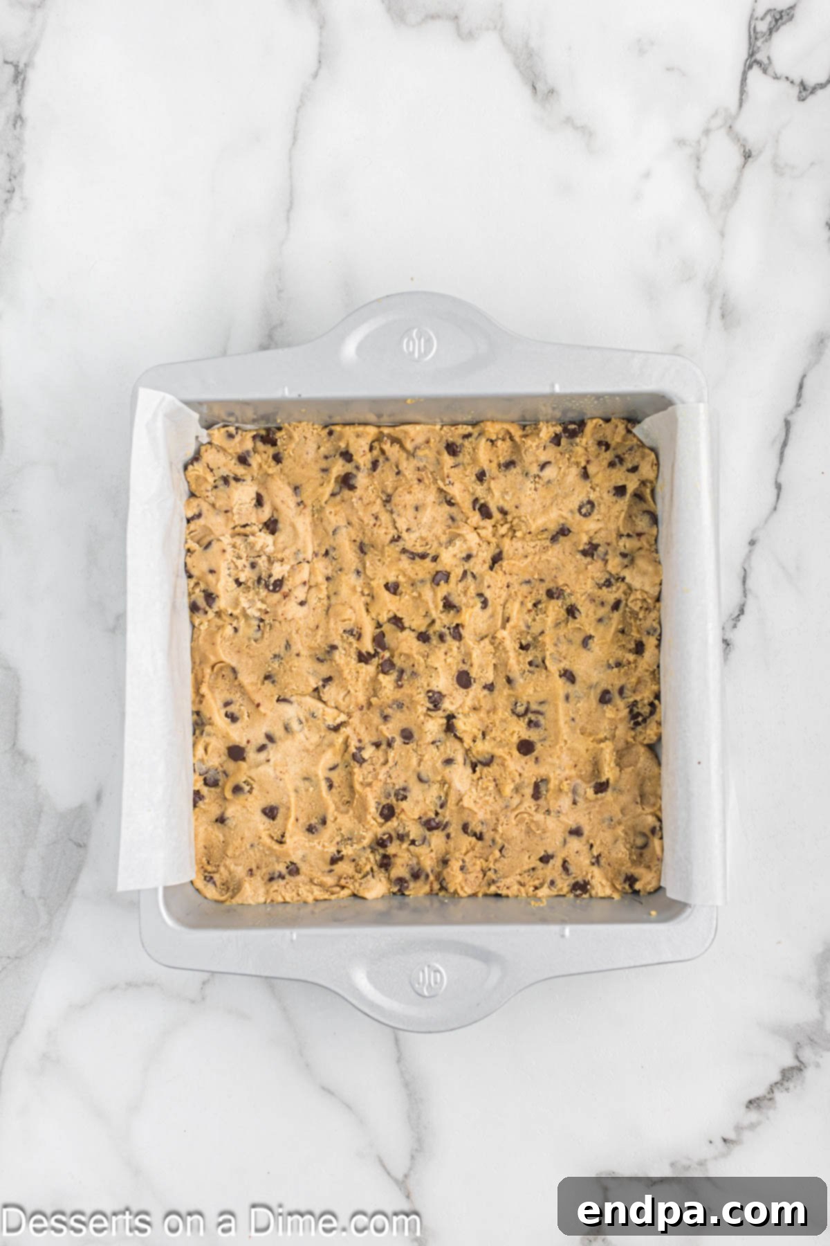 Baking dish with chocolate chip cookie dough pressed into the bottom as the first layer.