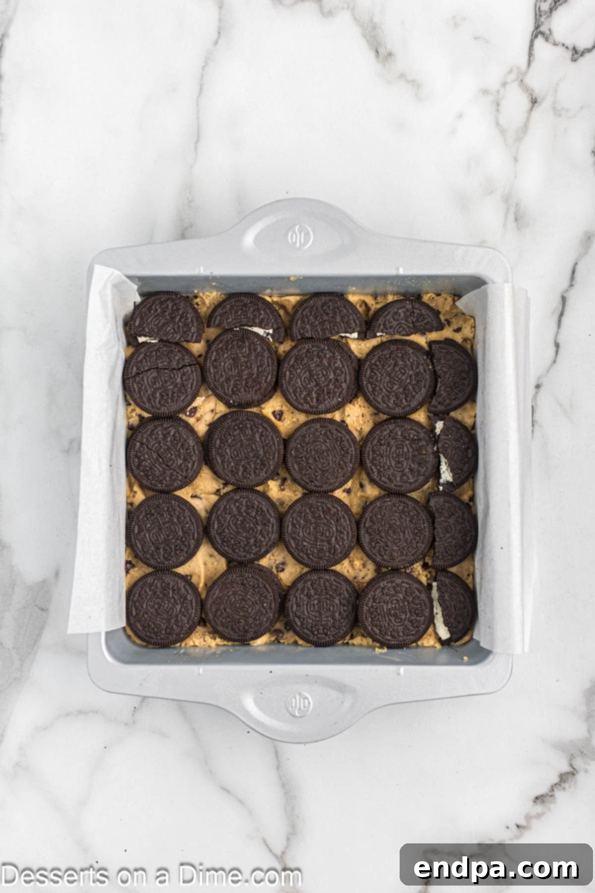Layer of Oreo cookies neatly arranged on top of the cookie dough in the baking dish.
