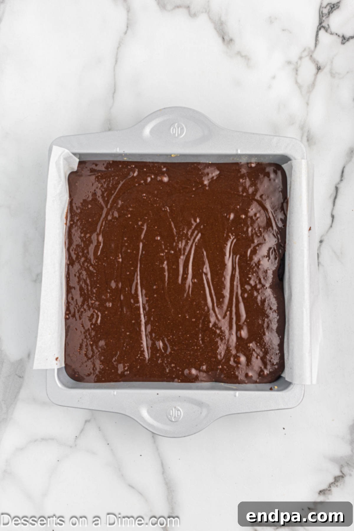 Brownie batter generously poured on top of the Oreo and cookie dough layers in the baking dish.