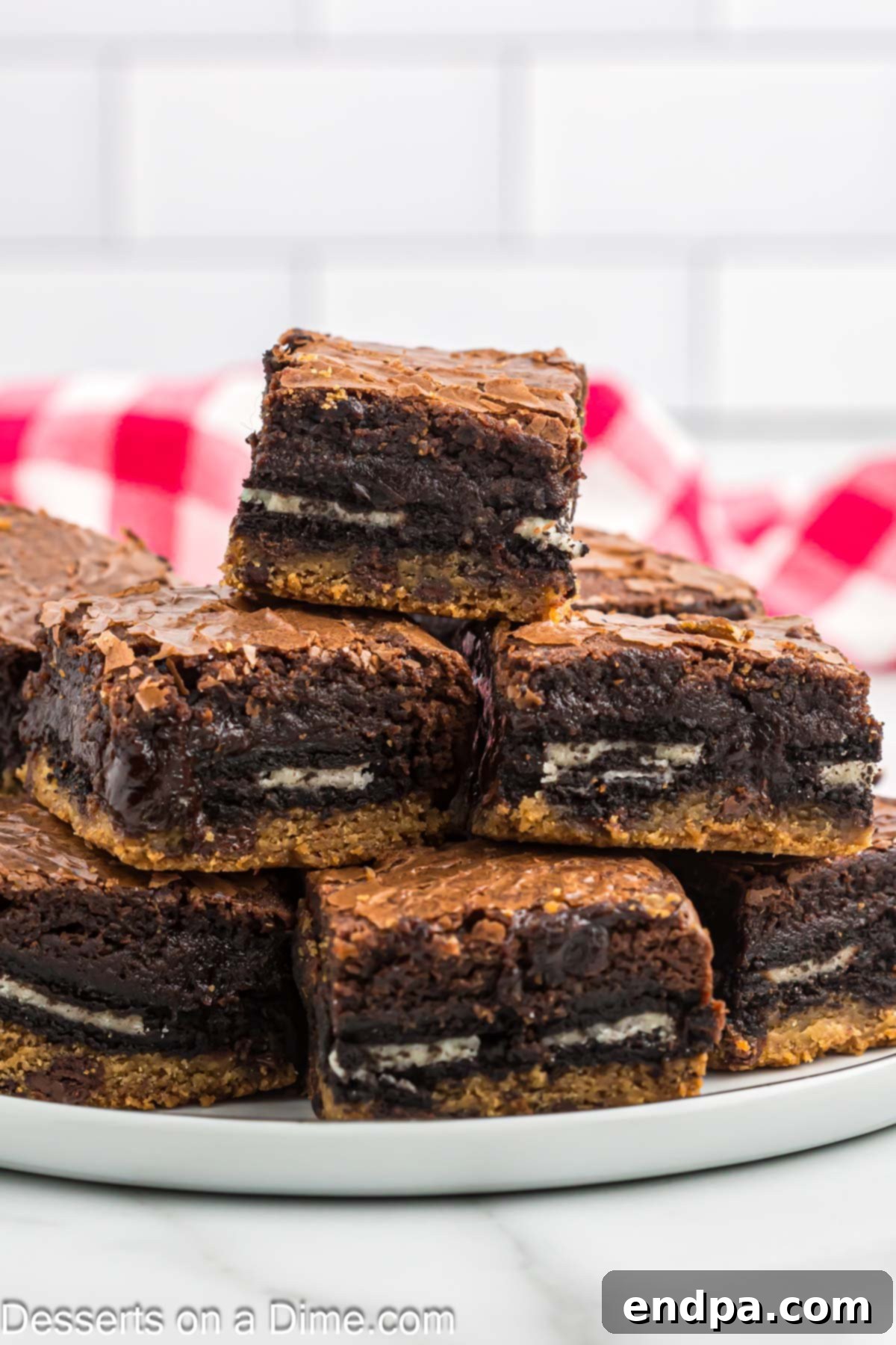 A stack of Slutty Brownies arranged on parchment paper, ready to be devoured.